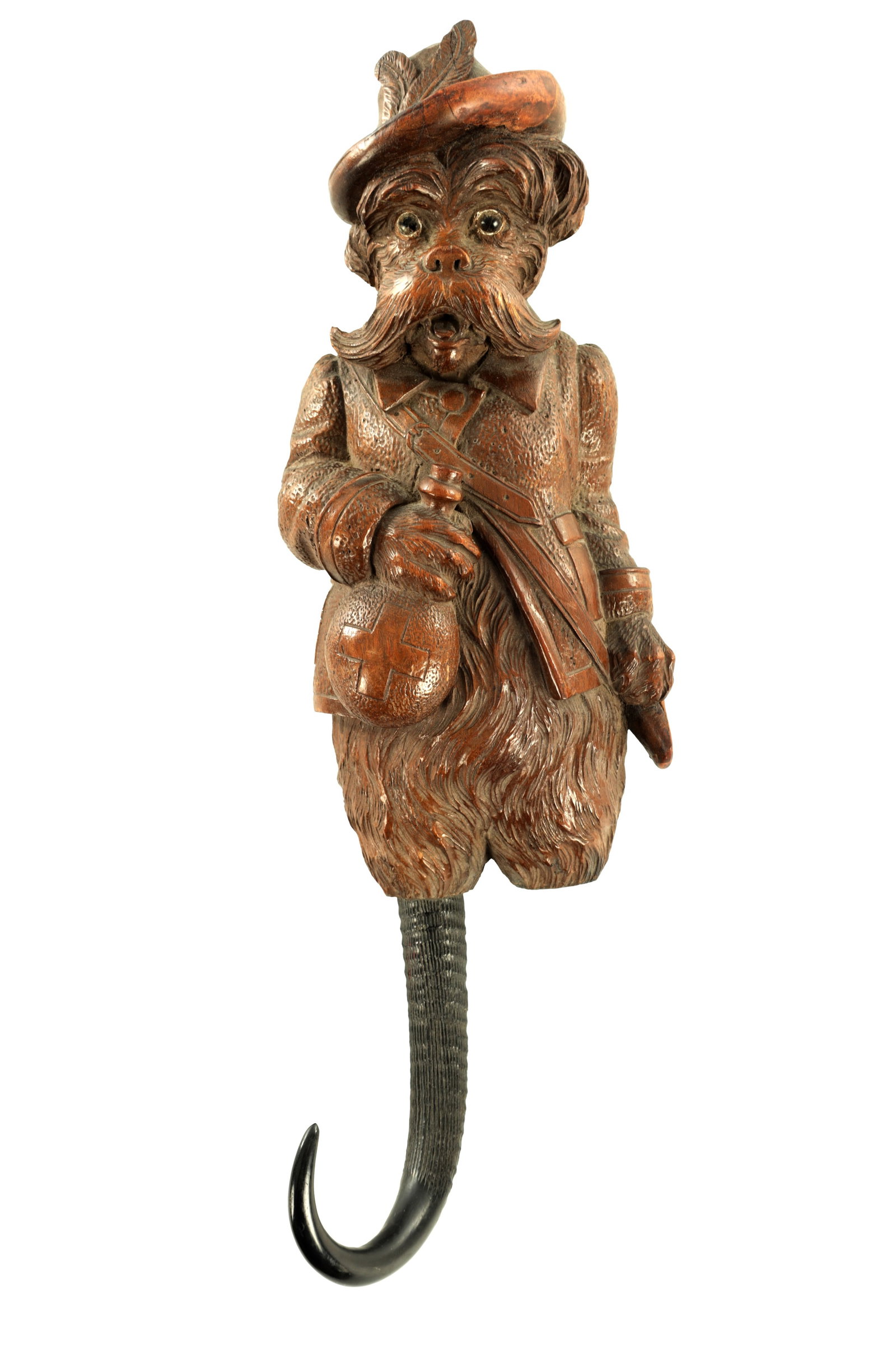 A LATE 19TH CENTURY BLACK FOREST CARVED WOOD COAT HOOK: A LATE 19TH CENTURY BLACK FOREST CARVED WOOD COAT HOOK modelled as a figural terrier in hunting attire holding a medicine flask and sachel, with glass eyes and a curved horn hook, one missing. (36cm l
