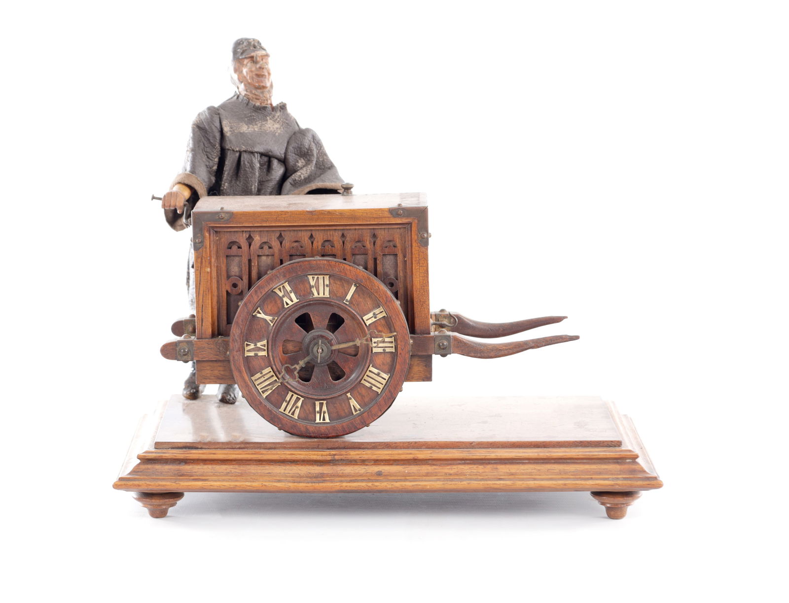 A LATE 19TH CENTURY GERMAN MUSICAL ORGAN CLOCK PLAYING A TUNE ON THE HOURS: A LATE 19TH CENTURY GERMAN MUSICAL ORGAN CLOCK PLAYING A TUNE ON THE HOURS modelled as a figure in a dark cloak pushing a Gothic-style barrel organ cart, the circular dial with Roman numerals set with
