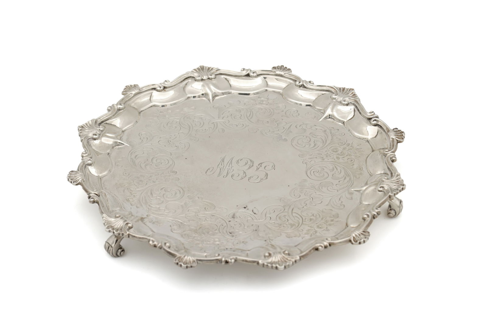 A MID 19TH CENTURY SILVER SALVER: A MID 19TH CENTURY SILVER SALVER of hexagonal form with scroll and shell work border surrounding foliate engraved decoration with initials engraved to the centre, raised on three acanthus leaf scrolle