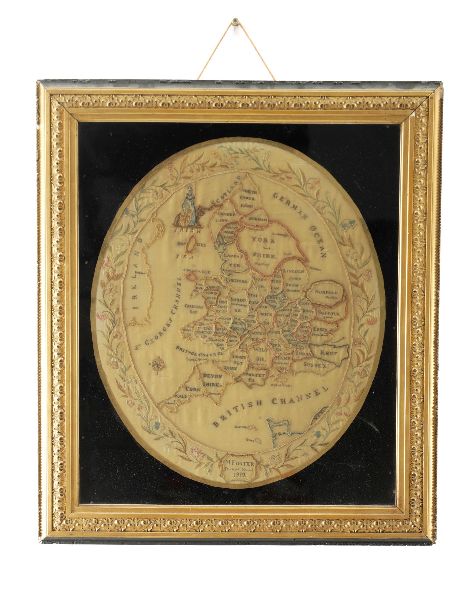 A GEORGE III SAMPLER OF A MAP OF BRITAIN: A GEORGE III SAMPLER OF A MAP OF BRITAIN by M.Foster from Dalestorth School, dated 1819, the map outlines all the counties in England, with a decorative floral embroidered border. Mounted in a moulded