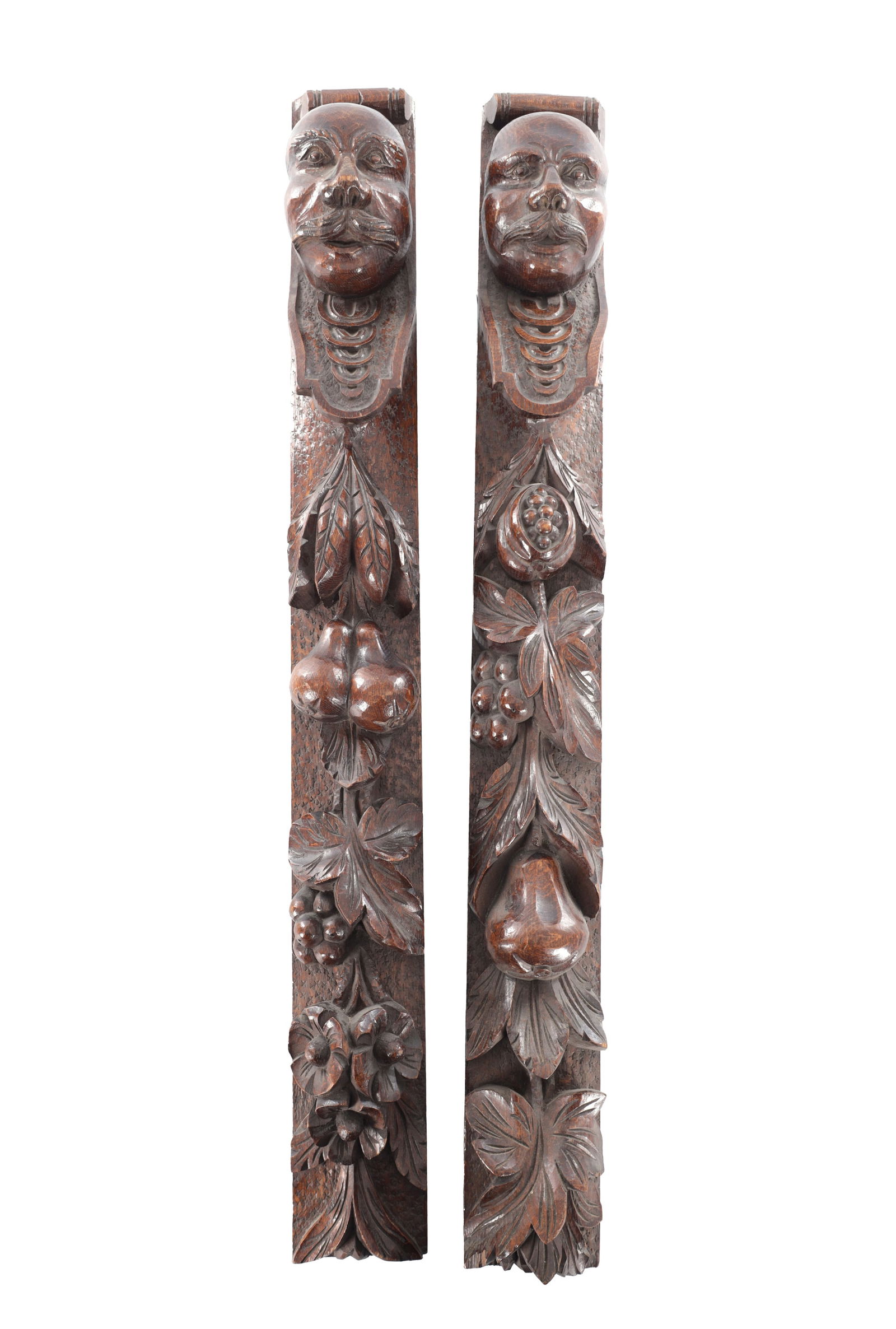 A PAIR OF 19TH CENTURY CARVED OAK CARYATID COLUMNS: A PAIR OF 19TH CENTURY CARVED OAK CARYATID COLUMNS each with a mask head above fruit veins. (86cm overall )
