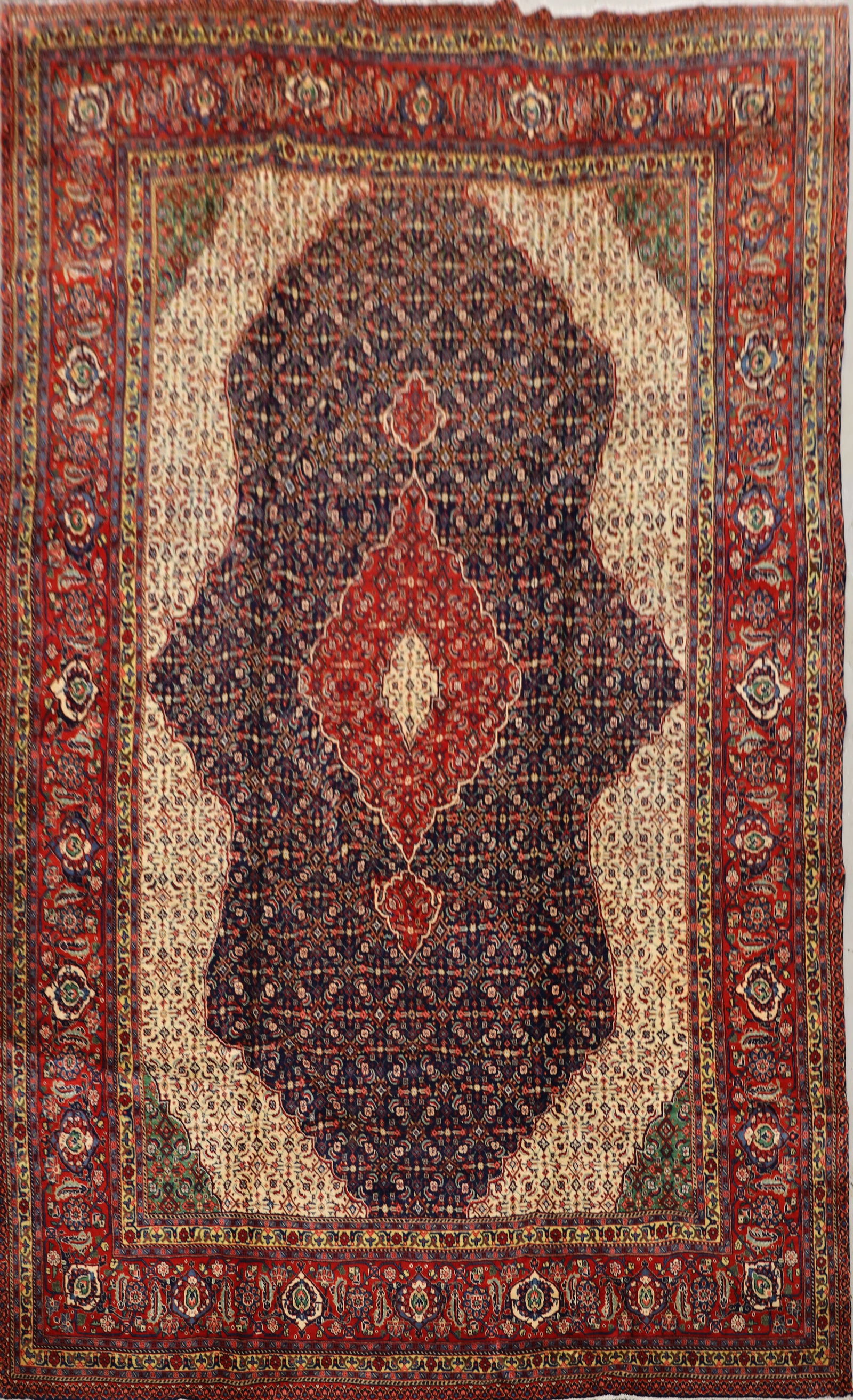 A HAND KNOTTED PERSIAN TABRIZ CARPET: A HAND KNOTTED PERSIAN TABRIZ CARPET having a Mahi pattern shown by the medallion and repeated floral and left motifs, made from wool, having deep red, blue, and lighter beige colours. (376cm by 280cm