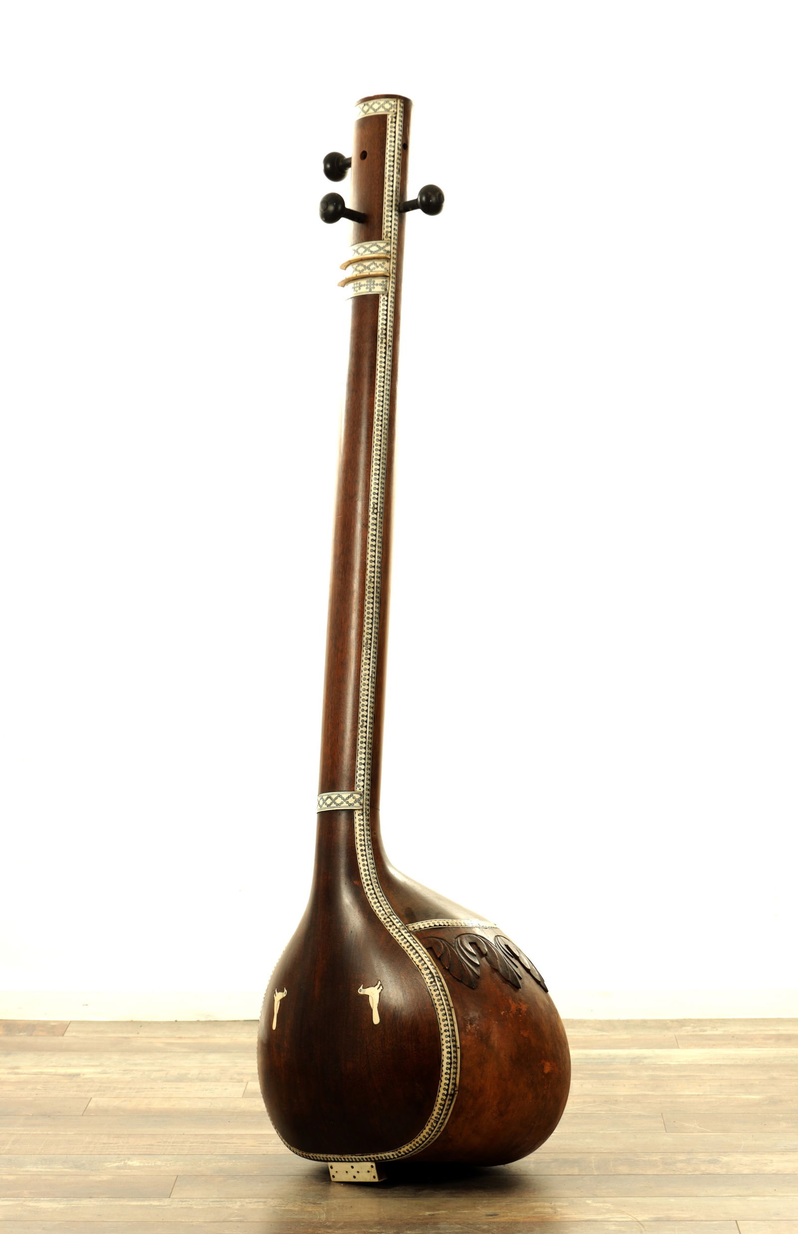 AN ANTIQUE BONE INLAID INDIAN HARDWOOD TAMBURA INSTRUMENT: AN ANTIQUE BONE INLAID INDIAN HARDWOOD TAMBURA INSTRUMENT, with a long cylindrical neck, the drum with inlaid birds and carved acanthus leaves on the reverse. (150cm high.)
