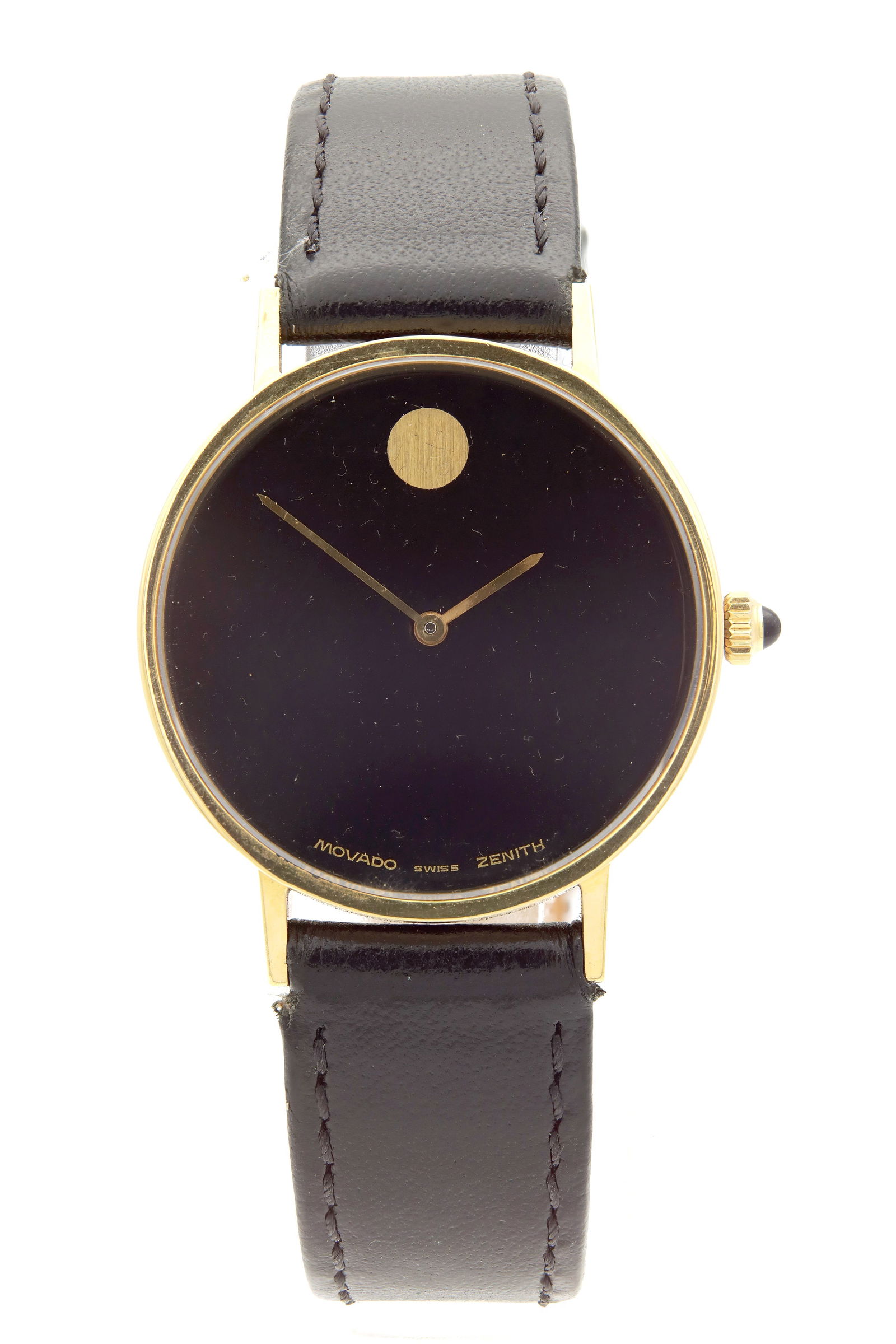 A GENTLEMAN'S 18CT GOLD MANUAL WIND MOVADO ZENITH WRISTWATCH: A GENTLEMAN'S 18CT GOLD MANUAL WIND MOVADO ZENITH WRISTWATCH, on a black leather strap. The circular case enclosing a black dial with gold hands, fronting a jewelled spring-driven movement. Total weig