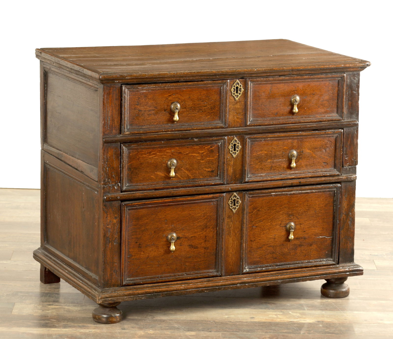 A 17TH-CENTURY OAK THREE DRAWER TWO-PART CHEST: A 17TH-CENTURY OAK THREE DRAWER TWO-PART CHEST with moulded graduated drawers fitted with brass pear drop handles, raised on bun feet (96cm wide 57cm deep 79cm high)