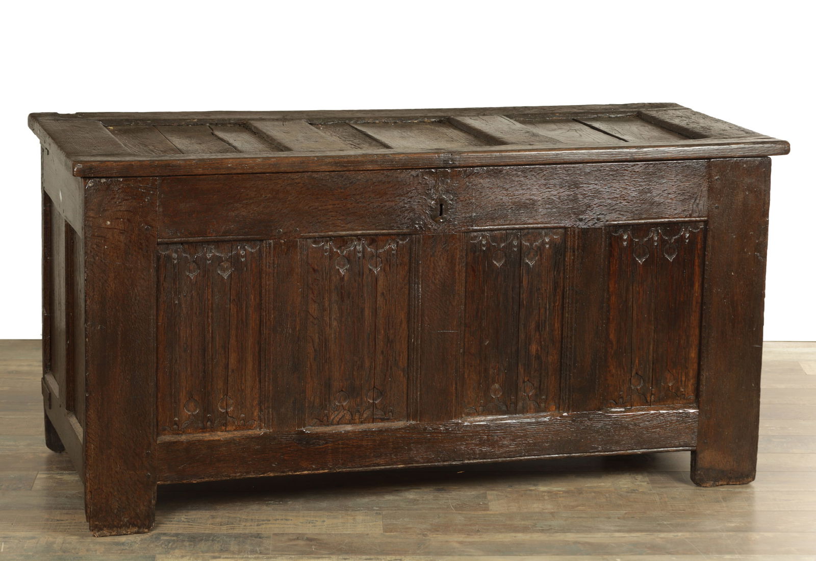 A 17TH CENTURY JOINED OAK PANELLED LINEN FOLD COFFER: A 17TH CENTURY JOINED OAK PANELLED LINEN FOLD COFFER with three-panel top above a lined fold carved front raised on stile feet. (148cm wide 62cm deep 74cm high)