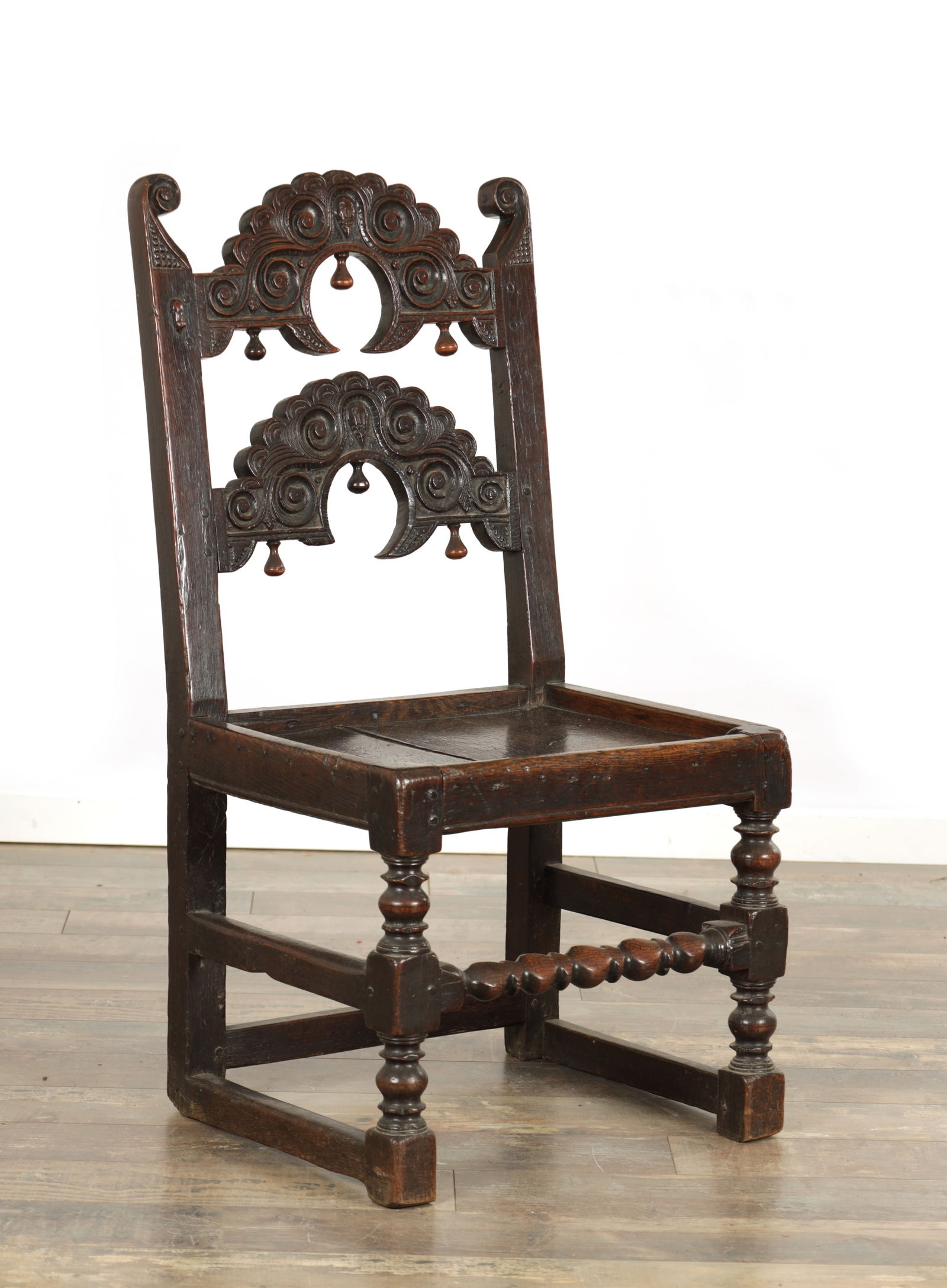 A 17TH CENTURY OAK SOUTH YORKSHIRE SIDE CHAIR: A 17TH CENTURY OAK SOUTH YORKSHIRE SIDE CHAIR with carved arched back above a panelled seat, raised on bobbin turned legs joined by stretchers (48cm wide 94cm high)