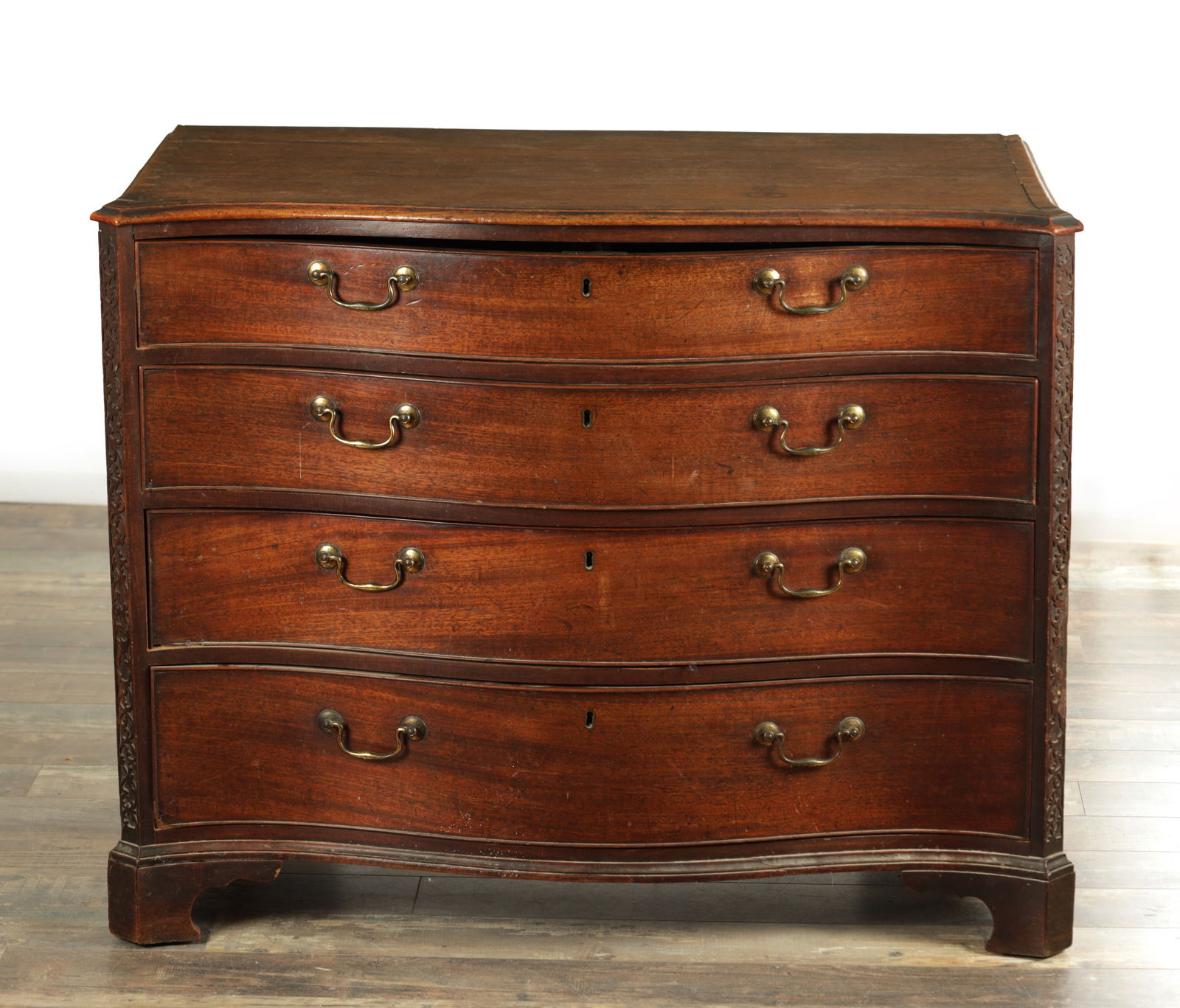 A GOOD GEORGE III MAHOGANY CHEST OF DRAWERS IN THE MANER OF THOMAS CHIPPENDALE: A GOOD GEORGE III MAHOGANY CHEST OF DRAWERS IN THE MANER OF THOMAS CHIPPENDALE with cross-banded top above four graduated drawers fitted with original brass swan-neck handles and raised on bracket fee