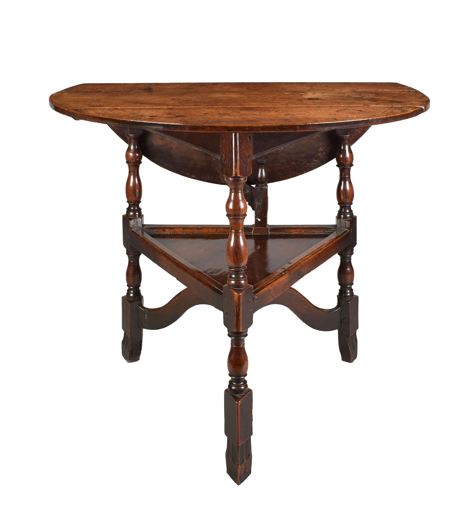 A RARE EARLY 18TH CENTURY OAK CRICKET TABLE: A RARE EARLY 18TH CENTURY OAK CRICKET TABLE with original hinged back raised on ring turned legs joined by an under-tier and shaped bottom stretcher and shaped feet. (68cm high 75cm diameter )