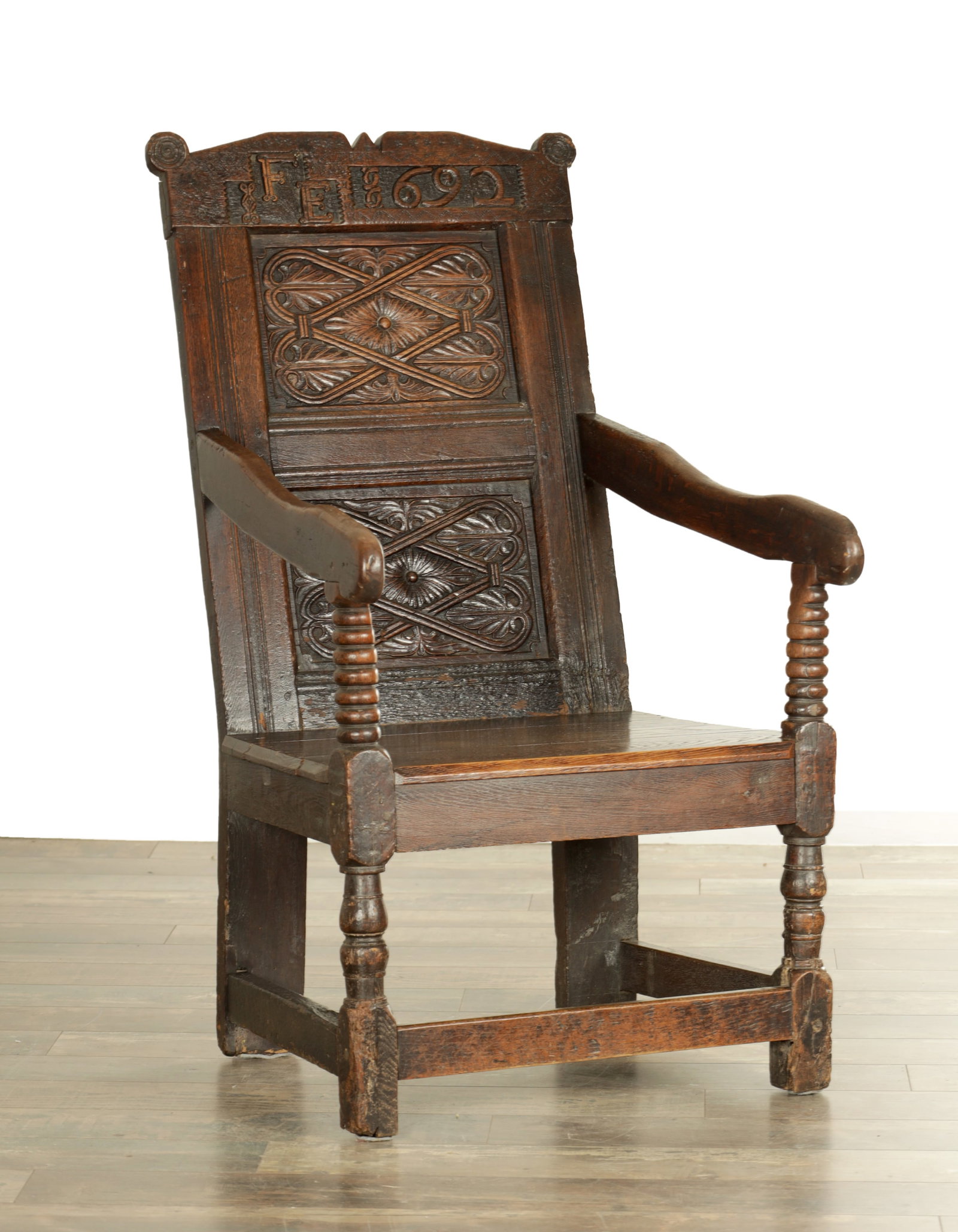 A 17TH CENTURY WESTMOORLAND DATED OAK WAINSCOT CHAIR: A 17TH CENTURY WESTMOORLAND DATED OAK WAINSCOT CHAIR with initialled and dated top rail for IFE 1692, above a carved panelled back and open arms raised on bobbin turned supports, with a later plank se