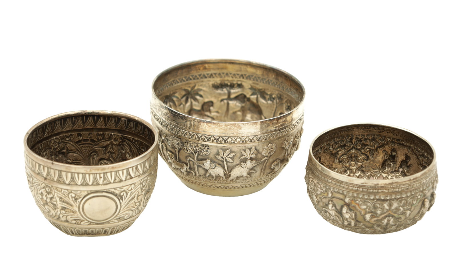 TWO INDIAN SILVER BOWLS AND ONE ENGLISH SILVER BOWL: TWO INDIAN SILVER BOWLS AND ONE ENGLISH SILVER BOWL all with embossed decoration, the larger bowl with a band of elephants, lions, and camels, the smaller decorated with figural panels amongst scrolli