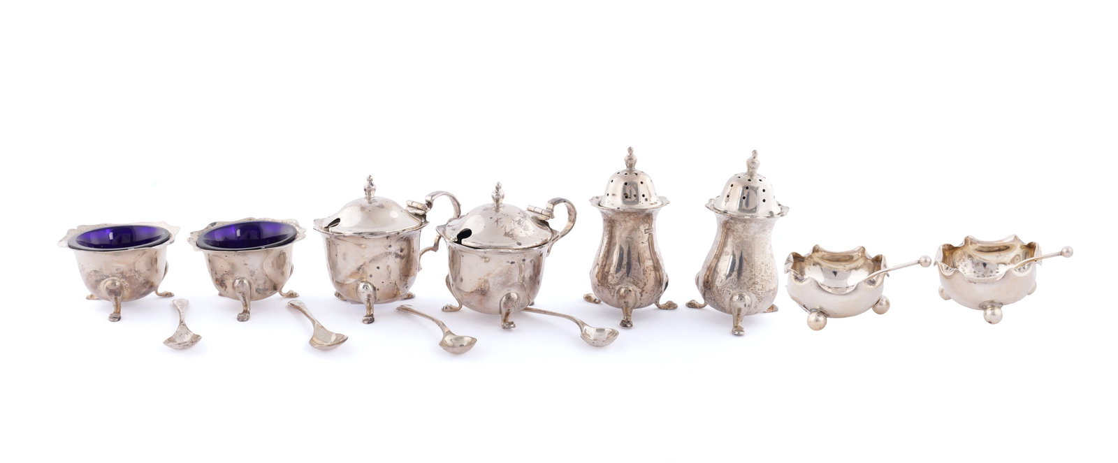 TWO CASED SILVER CRUET SETS: TWO CASED SILVER CRUET SETS one 6 piece with casters, mustard pots and condiment lidded pots and spoons of scalloped design, the other with two condiment pots and spoons with ball feet and roll over r