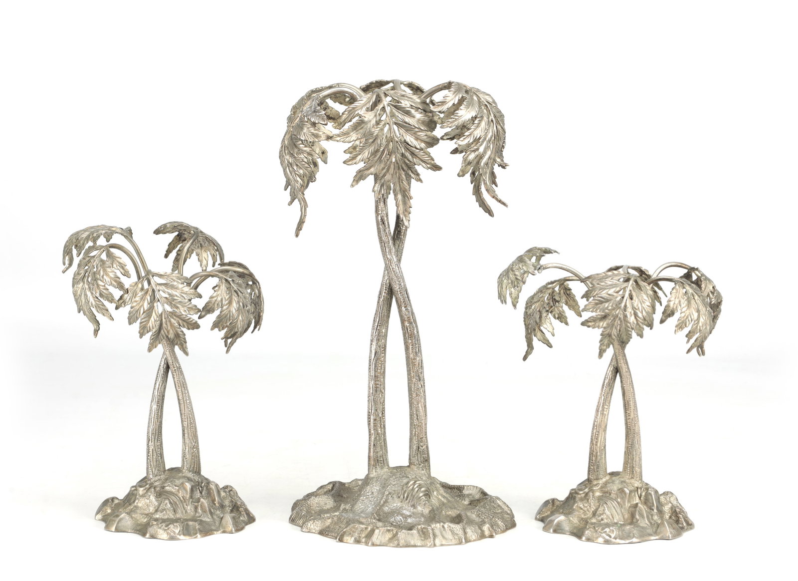 THREE LATE VICTORIAN SILVER PLATED PALM TREE TABLE ORNAMENTS ON NATURALISTIC BASES: THREE LATE VICTORIAN SILVER PLATED PALM TREE TABLE ORNAMENTS ON NATURALISTIC BASES each modelled with twin trunks and pendant fronds rising from rocky mounds, the group graduated with a larger central