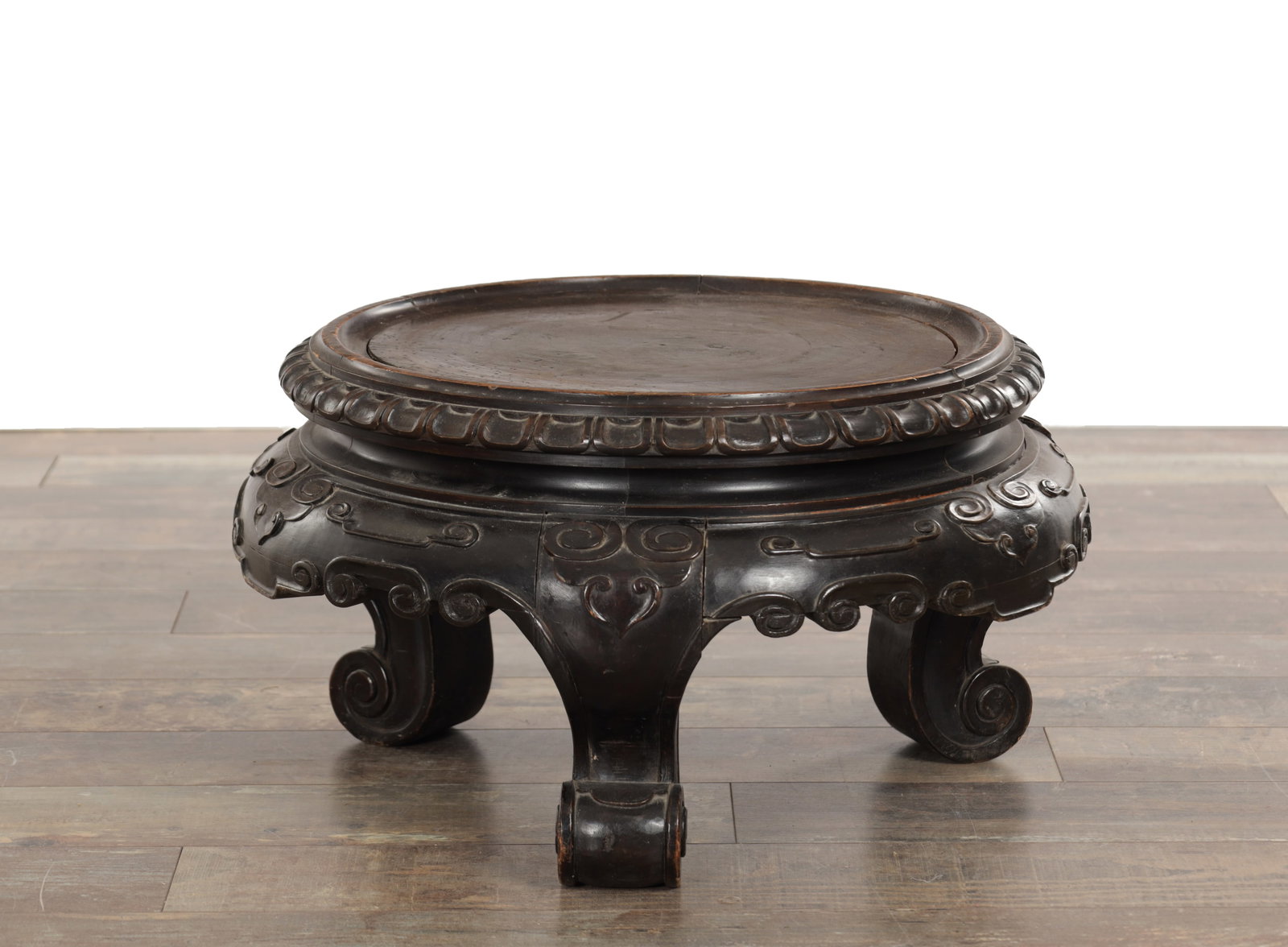 A LARGE 19TH CENTURY CHINESE HARDWOOD JARDINIERE STAND: A LARGE 19TH CENTURY CHINESE HARDWOOD JARDINIERE STAND the circular top with a raised rim above a deeply carved apron decorated with stylised scroll motifs, raised on bold carved scroll supports termi