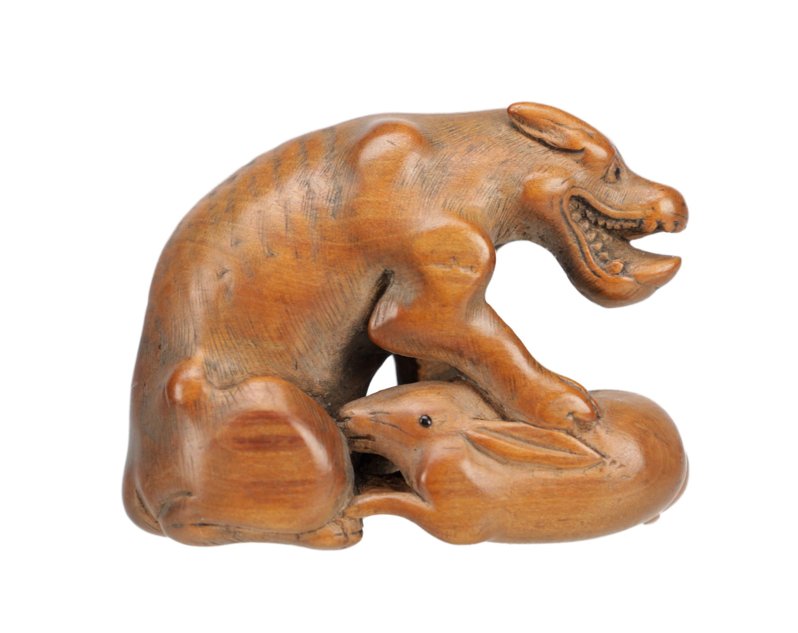 A MEIJI PERIOD JAPANESE BOXWOOD NETSUKE AS A DOG CATCHING A RABBIT: A MEIJI PERIOD JAPANESE BOXWOOD NETSUKE AS A DOG CATCHING A RABBIT finely carved with bared teeth and incised fur, the hare pinned beneath its forepaws. (4cm high 5cm across)