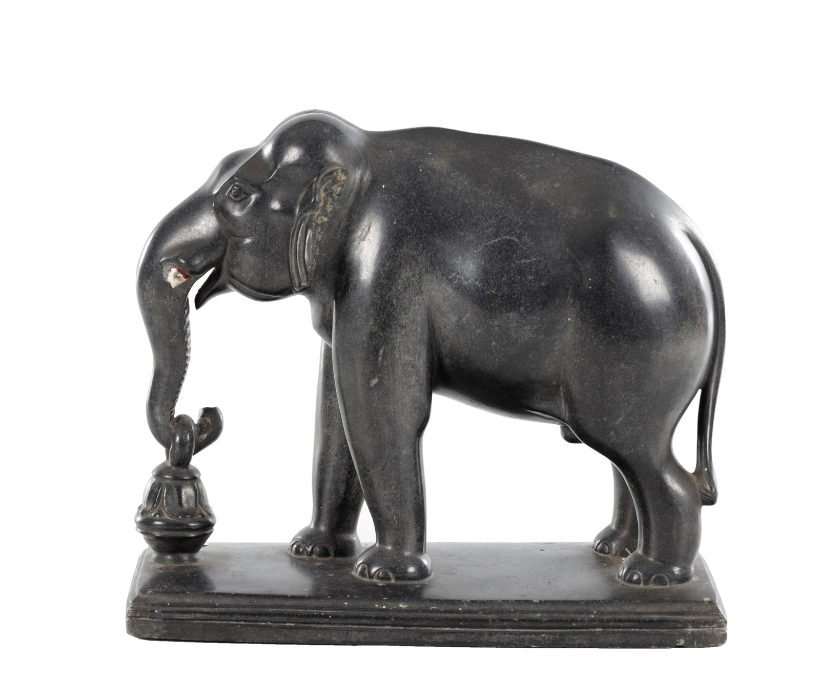 AN 18TH/19TH CENTURY INDIAN BLACK PORPHYRY ELEPHANT SCULPTURE ON A STEPPED BASE: AN 18TH/19TH CENTURY INDIAN BLACK PORPHYRY ELEPHANT SCULPTURE ON A STEPPED BASE modelled standing four-square with the trunk lowered and coiled to suspend a small bell-shaped vessel, with carved facia