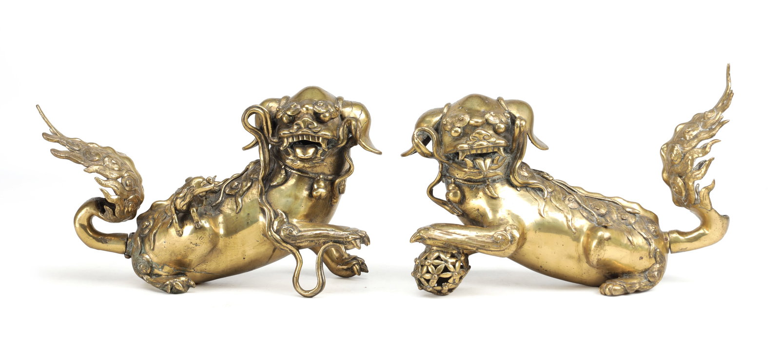 A PAIR OF 17TH CENTURY CHINESE BRONZE BUDDHIST LIONS: A PAIR OF 17TH CENTURY CHINESE BRONZE BUDDHIST LIONS modelled recumbent with collars, bells and trailing ribbons, each with a flame-form tail, the male with a reticulated brocade ball and the female w