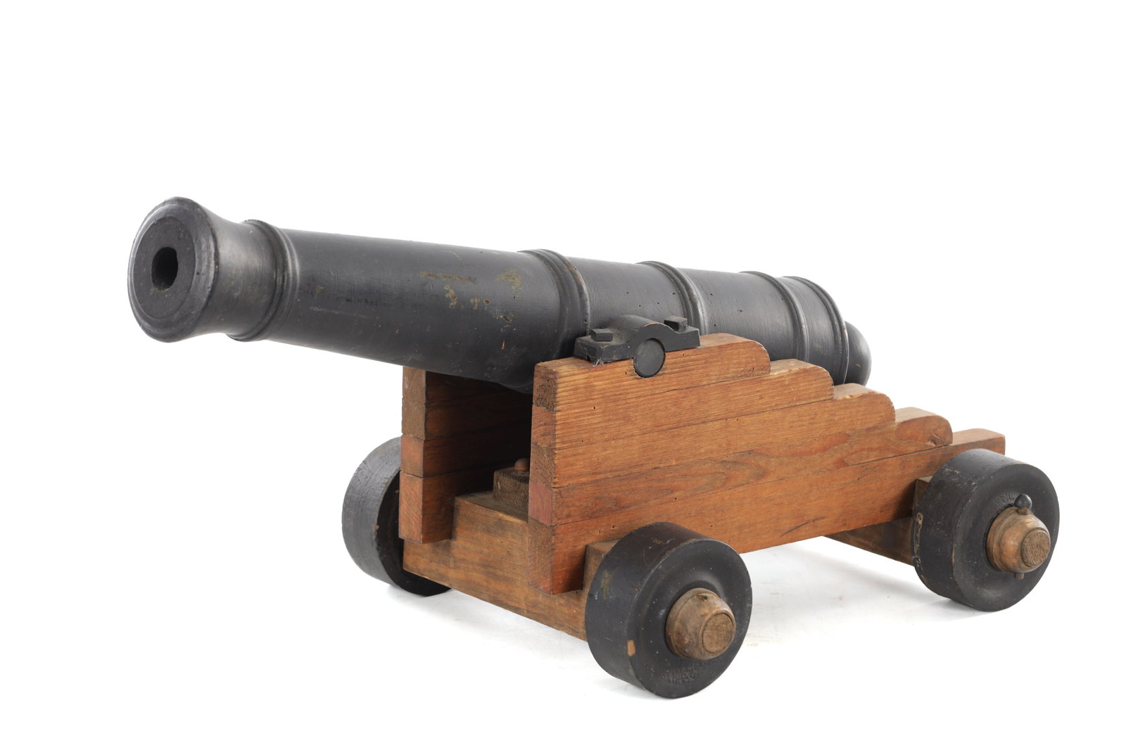 A 20TH CENTURY WOODEN MODEL CANNON ON A CARRIAGE: A 20TH CENTURY WOODEN MODEL CANNON ON A CARRIAGE the barrel of typical tapered form with ring turned bands and a rounded cascabel, mounted within a stepped wooden carriage with block supports and rais