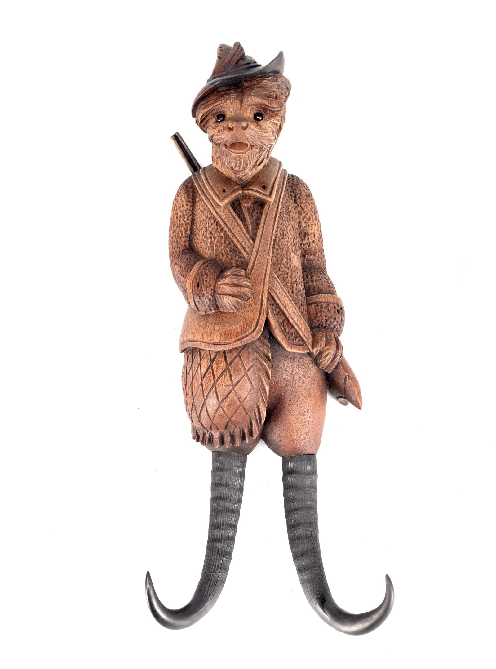 A 19TH CENTURY BLACK FOREST CARVED WOOD DOG HUNTSMAN COAT HOOK WITH TWIN HORN-FORM HOOKS: A 19TH CENTURY BLACK FOREST CARVED WOOD DOG HUNTSMAN COAT HOOK WITH TWIN HORN-FORM HOOKS carved as an anthropomorphic dog dressed as a huntsman wearing a hat and jacket with cross-hatched breeches, a