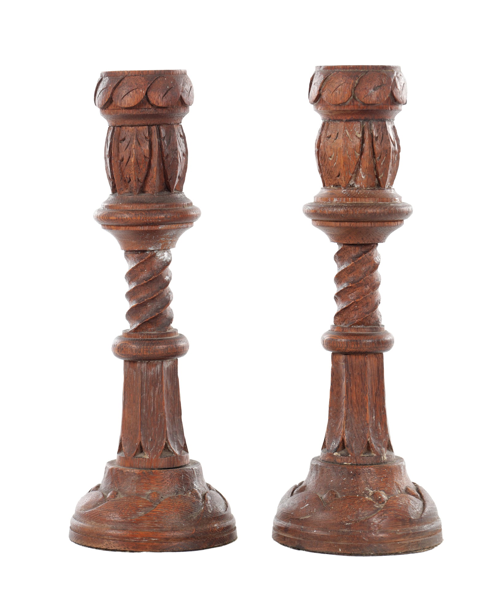 A PAIR OF 19TH CENTURY GOTHIC REVIVAL CARVED OAK CANDLESTICKS: A PAIR OF 19TH CENTURY GOTHIC REVIVAL CARVED OAK CANDLESTICKS each with a circular socket above a carved foliate knop and spiral twist stem, raised on a faceted column and spreading circular base carv
