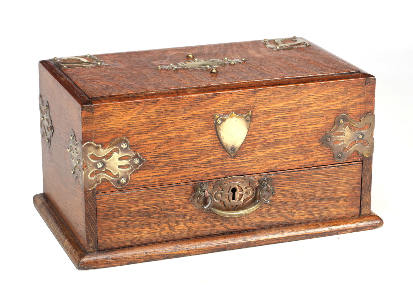 A LATE 19TH CENTURY ARTS AND CRAFTS OAK HUMIDOR WITH BRASS MOUNTS: A LATE 19TH CENTURY ARTS AND CRAFTS OAK HUMIDOR WITH BRASS MOUNTS of rectangular form with pierced strapwork corner and lid mounts and a vacant shield cartouche, the hinged lid above a frieze drawer w