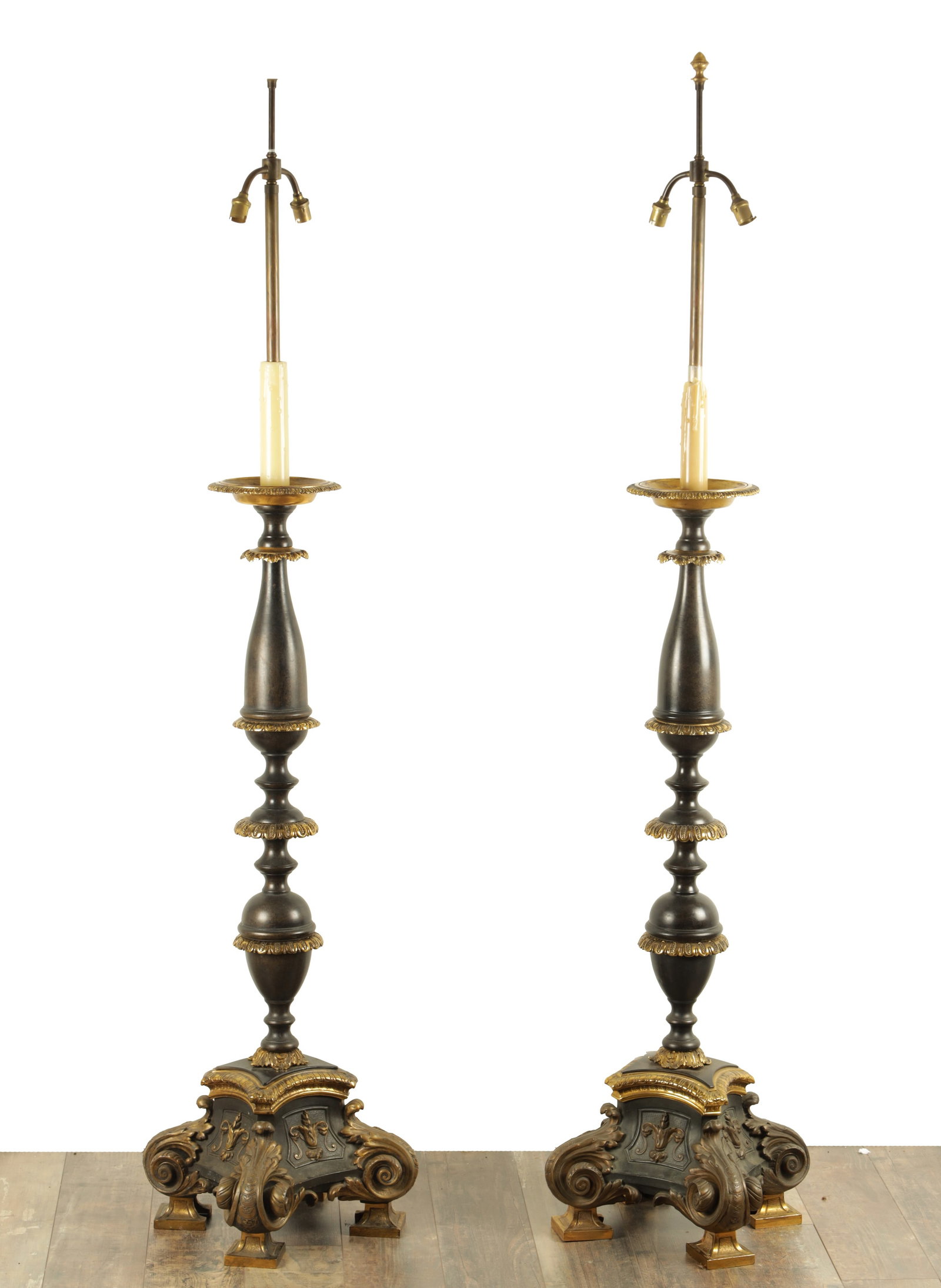 AN IMPRESSIVE PAIR OF 19TH CENTURY BRONZE AND GILT BRONZE TORCHERE STANDARD LAMPS: AN IMPRESSIVE PAIR OF 19TH CENTURY BRONZE AND GILT BRONZE TORCHERE STANDARD LAMPS the dished tops with leaf work collars to the tapering knopped stems on elaborate scrolled leaf work raised panelled b