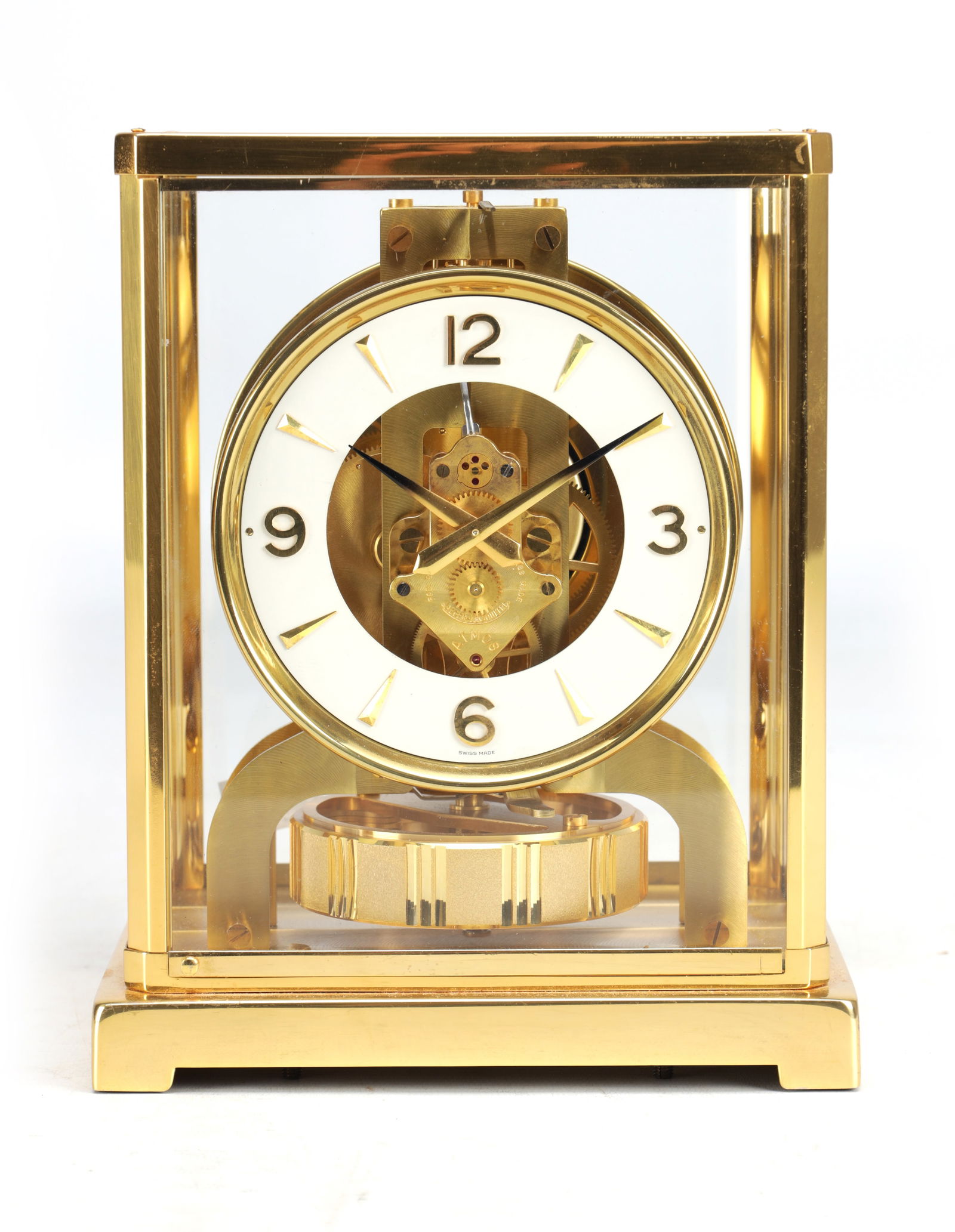 A SWISS GILT BRASS AND GLASS ATMOS CLOCK: A SWISS GILT BRASS AND GLASS ATMOS CLOCK of rectangular form with four glazed sides and a hinged front door, the circular white chapter ring with applied Arabic quarters and baton markers enclosing th
