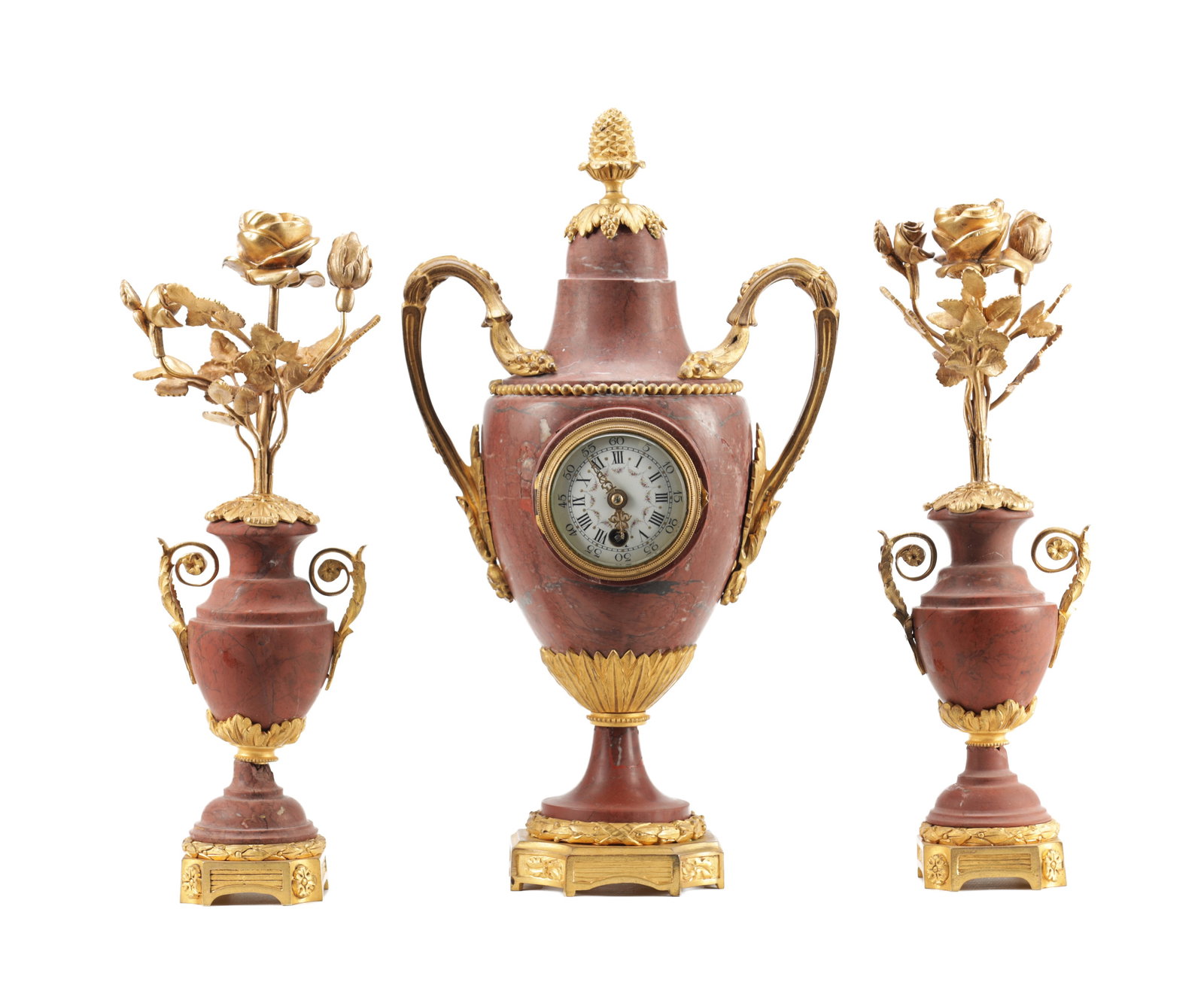 A LATE 19TH CENTURY ROUGE MARBLE AND ORMOLU MOUNTED THREE PIECE CLOCK GARNITURE: A LATE 19TH CENTURY ROUGE MARBLE AND ORMOLU MOUNTED THREE PIECE CLOCK GARNITURE comprising a central urn-form mantel timepiece with pinecone finial, twin scroll handles and laurel cast mounts, the cir