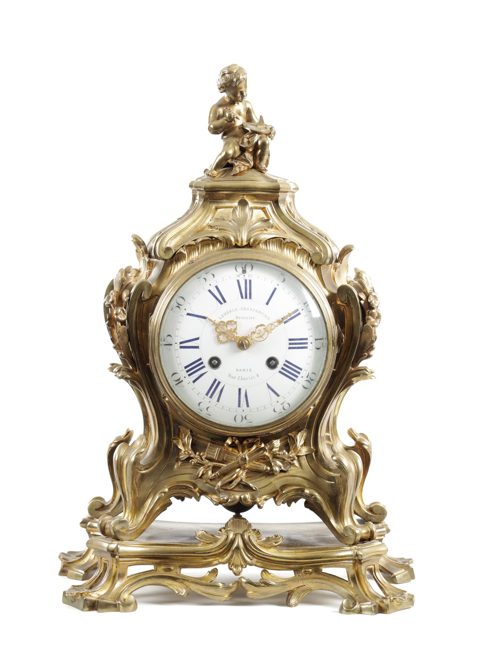 A 19TH CENTURY FRENCH GILT BRASS ROCOCO STYLE MANTEL CLOCK: A 19TH CENTURY FRENCH GILT BRASS ROCOCO STYLE MANTEL CLOCK the case surmounted by a seated cherub above a circular enamel dial with blue Roman numerals and gilt hands, signed Lemerle-Charpentier Bronz