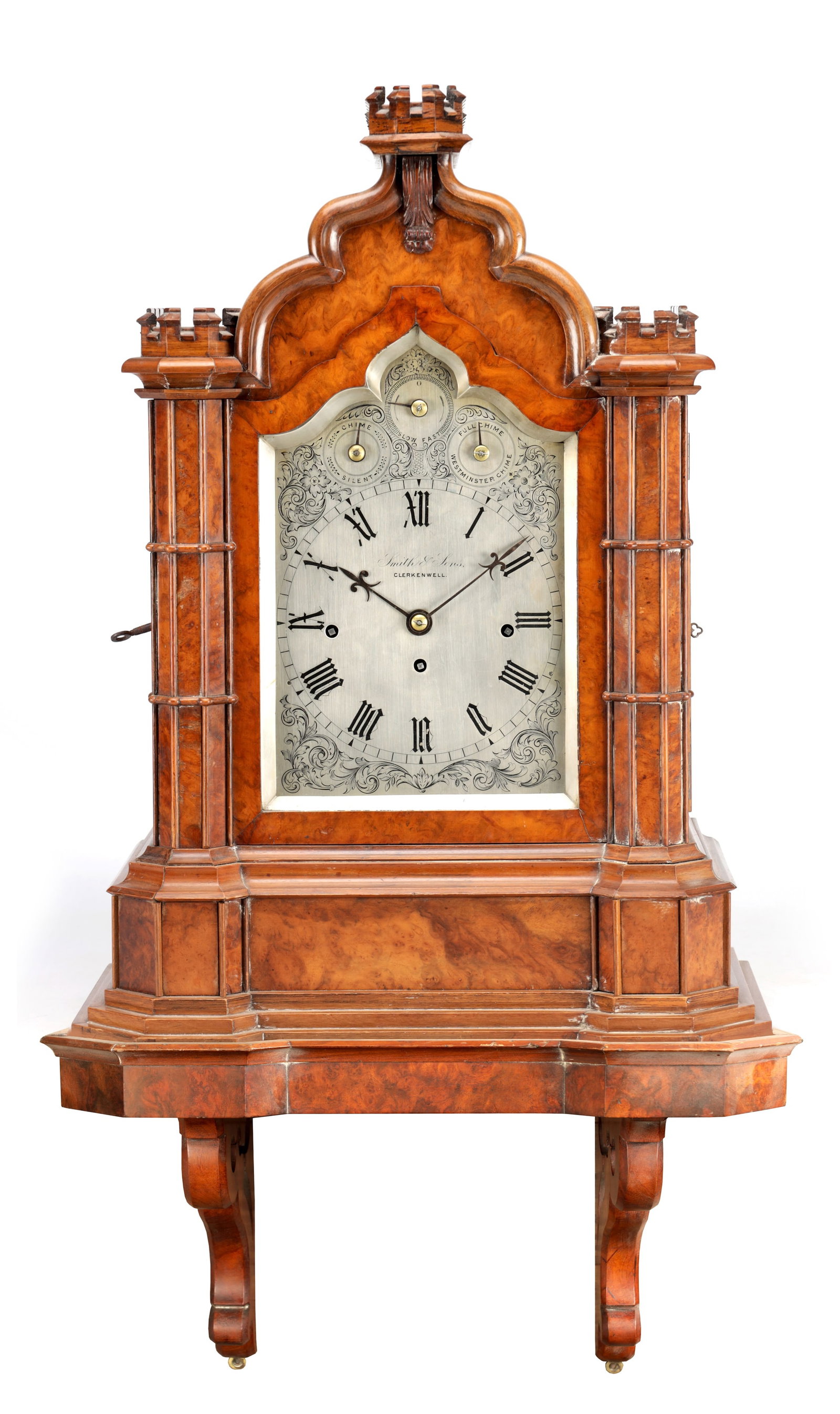 A VICTORIAN BURR WALNUT THREE TRAIN BRACKET CLOCK WITH WALL BRACKET: A VICTORIAN BURR WALNUT THREE TRAIN BRACKET CLOCK WITH WALL BRACKET the silvered dial signed Smith & Sons Clerkenwell with Roman numerals and foliate engraving, having an eight day chain driven triple