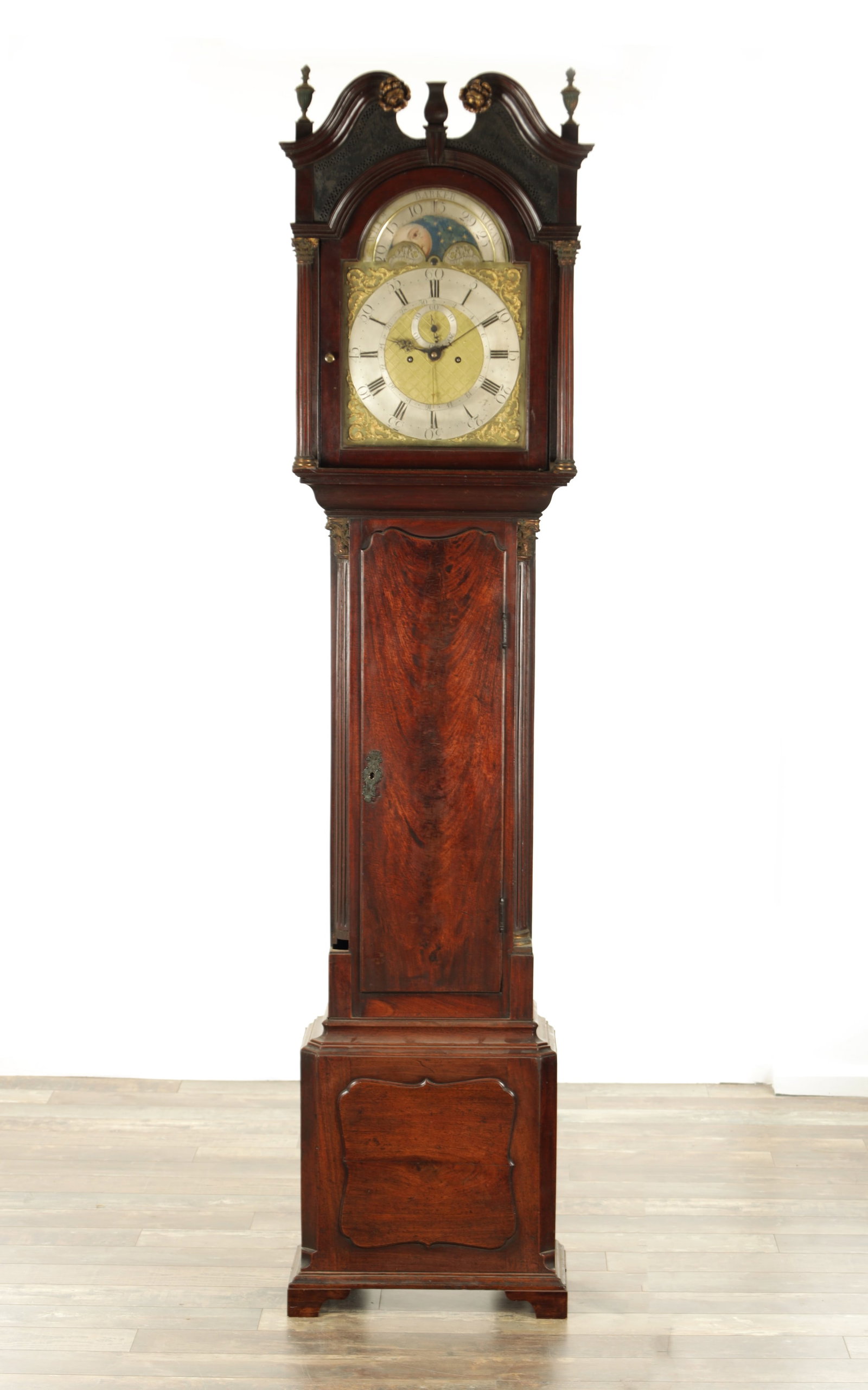 WILLIAM BARKER, WIGAN. A GEORGE III FIGURED MAHOGANY LONGCASE CLOCK: WILLIAM BARKER, WIGAN. A GEORGE III FIGURED MAHOGANY LONGCASE CLOCK the hood with swan neck pediment above a glazed door flanked by brass-capped reeded Corinthian columns, the matching trunk and box b