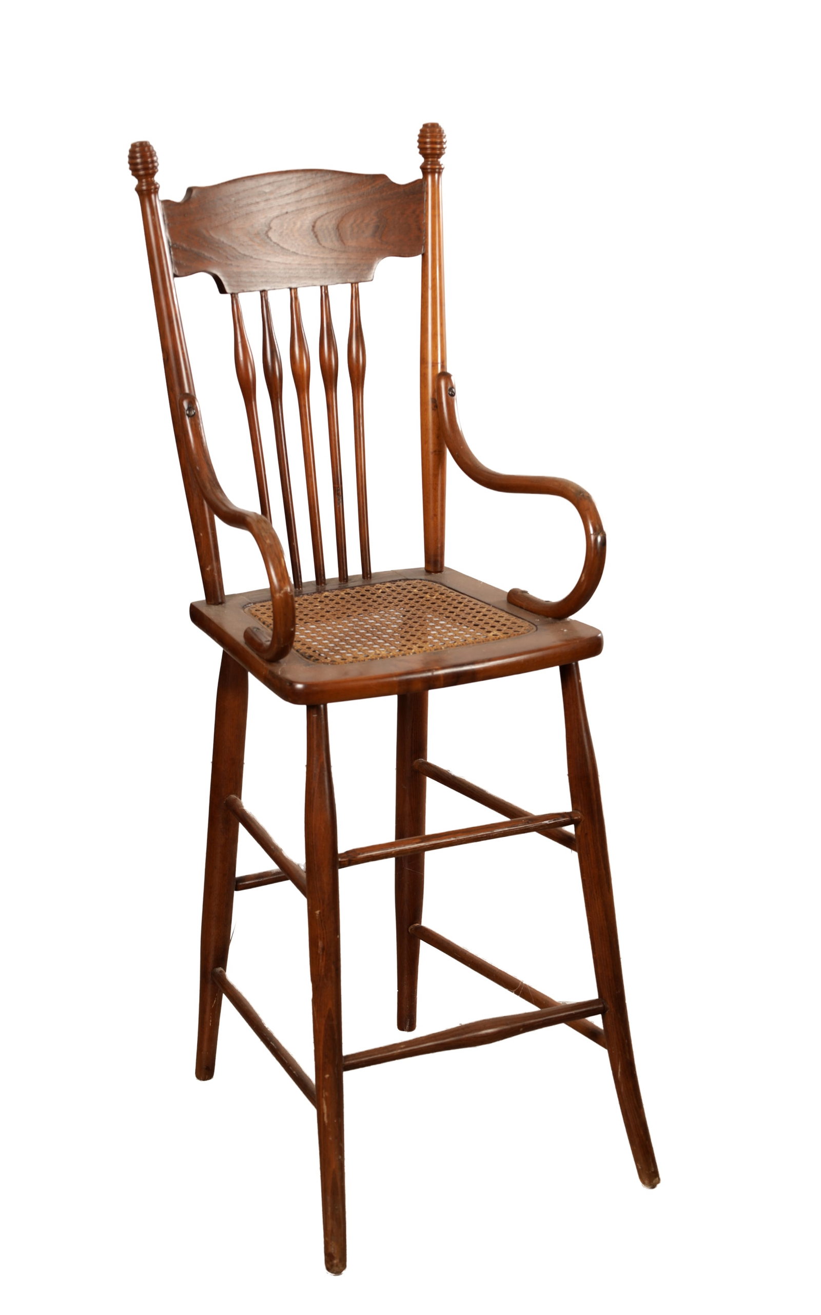 AN EARLY 20TH CENTURY AMERICAN CHILD'S HIGH CHAIR WITH CANE SEAT: AN EARLY 20TH CENTURY AMERICAN CHILD'S HIGH CHAIR WITH CANE SEAT the shaped top rail above five baluster spindles between turned uprights with knop finials, with scrolled arms, the woven cane seat ove