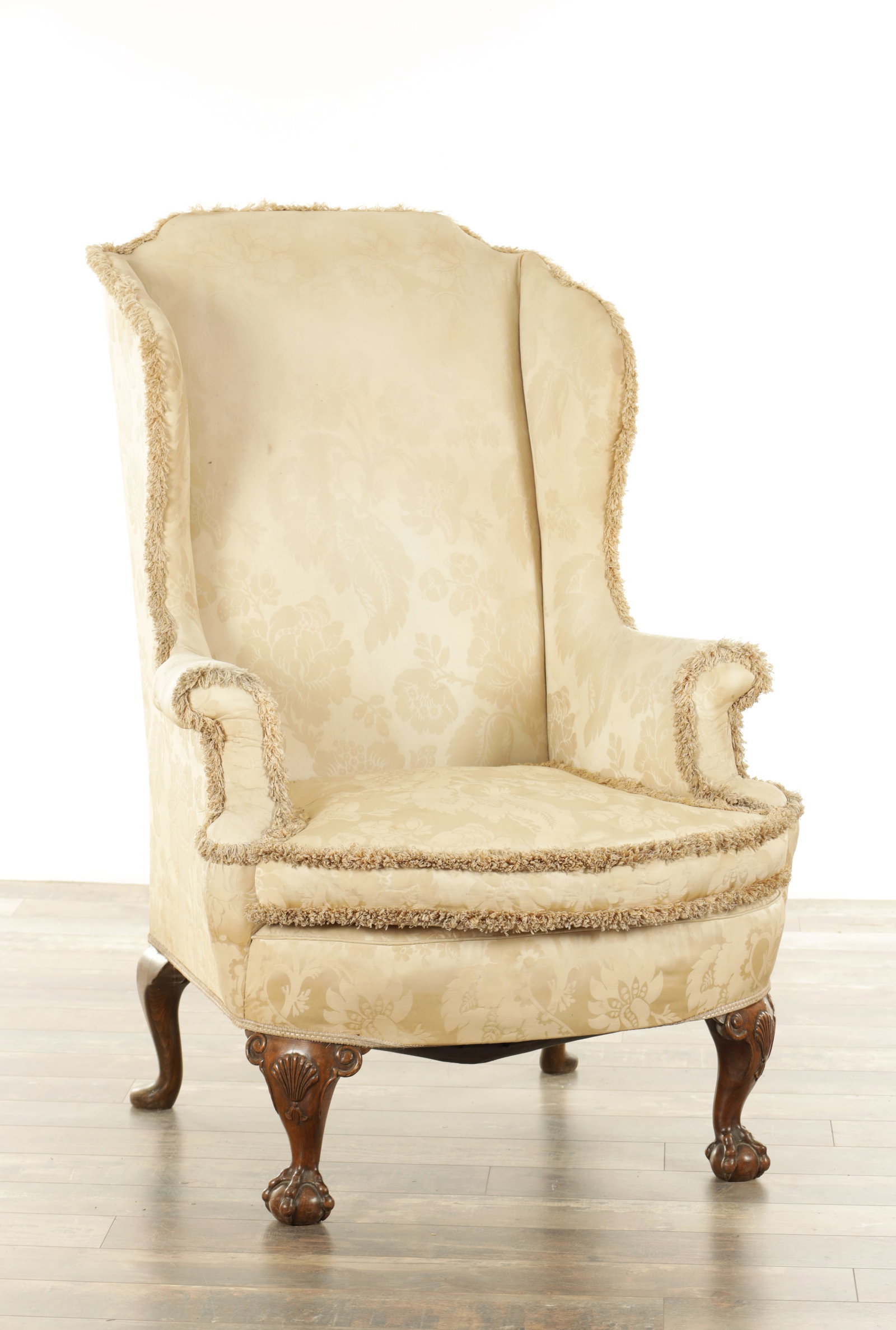 A GEORGIAN STYLE CARVED WALNUT WING-BACK UPHOLSTERED ARMCHAIR: A GEORGIAN STYLE CARVED WALNUT WING-BACK UPHOLSTERED ARMCHAIR with loose cushion seat, standing on short shell carved cabriole legs with ball and claw feet (82cm wide 120cm high )