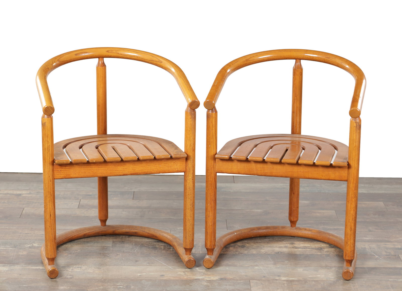 A PAIR OF 1980S POSTMODERN GERMAN BENTWOOD DINING ARMCHAIRS FOR ALLMILMO: A PAIR OF 1980S POSTMODERN GERMAN BENTWOOD DINING ARMCHAIRS FOR ALLMILMO with curved horseshoe backs and short arms above moulded slatted seats, raised on cylindrical legs joined by a semi-circular st
