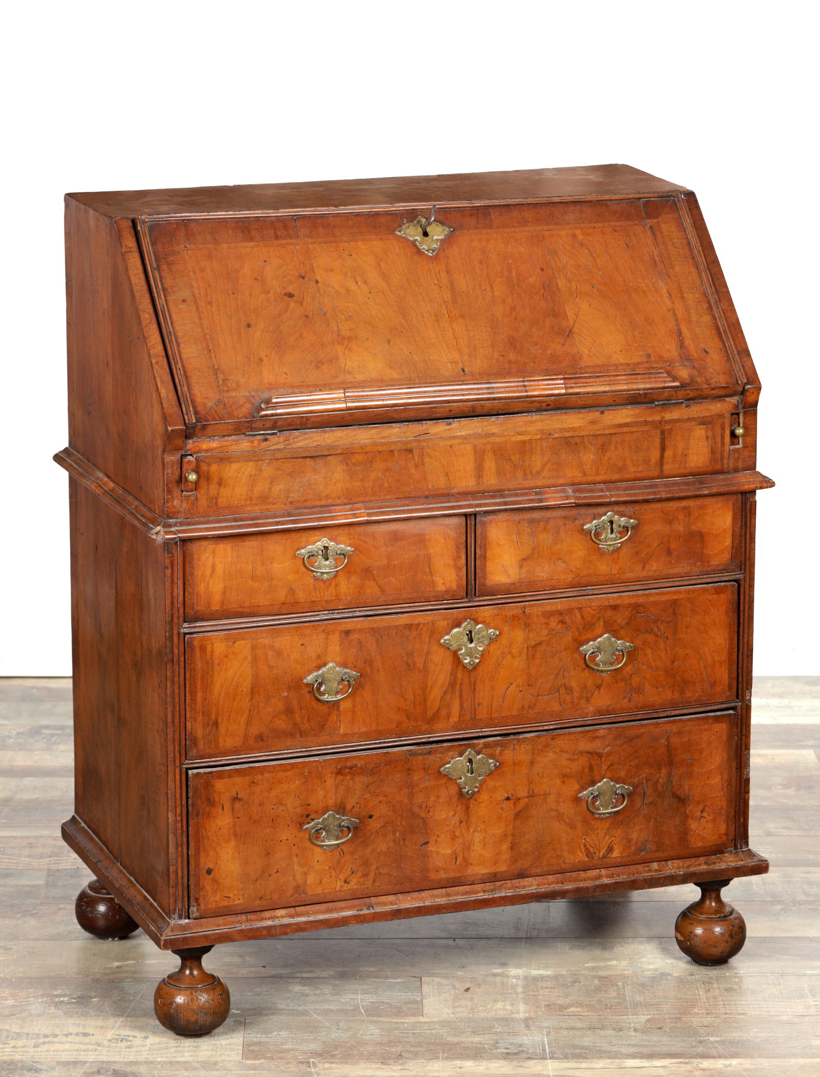 A WILLIAM AND MARY WALNUT BUREAU OF SMALL SIZE: A WILLIAM AND MARY WALNUT BUREAU OF SMALL SIZE with a sloping fall with moulded edge and brass escutcheon, fitted with side lopers, above two short and two long drawers with brass escutcheons and drop