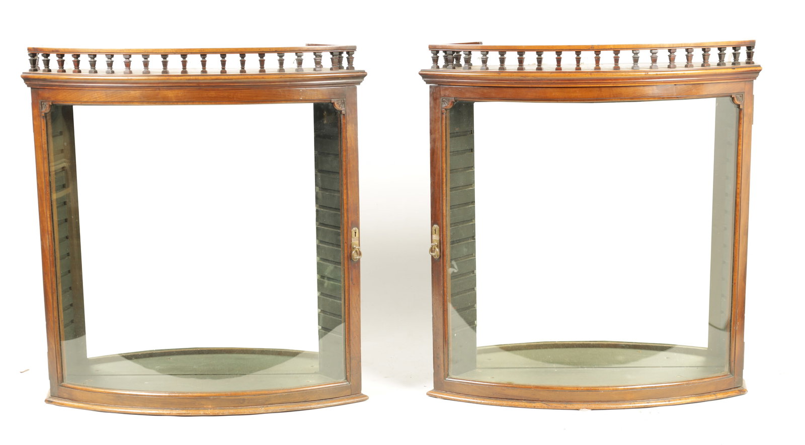 A PAIR OF 19TH CENTURY MAHOGANY BOW FRONTED DISPLAY CABINETS: A PAIR OF 19TH CENTURY MAHOGANY BOW FRONTED DISPLAY CABINETS with gallery tops and hinged doors revealing glass shelves and mirrored backs. (74cm wide and 76cm high)