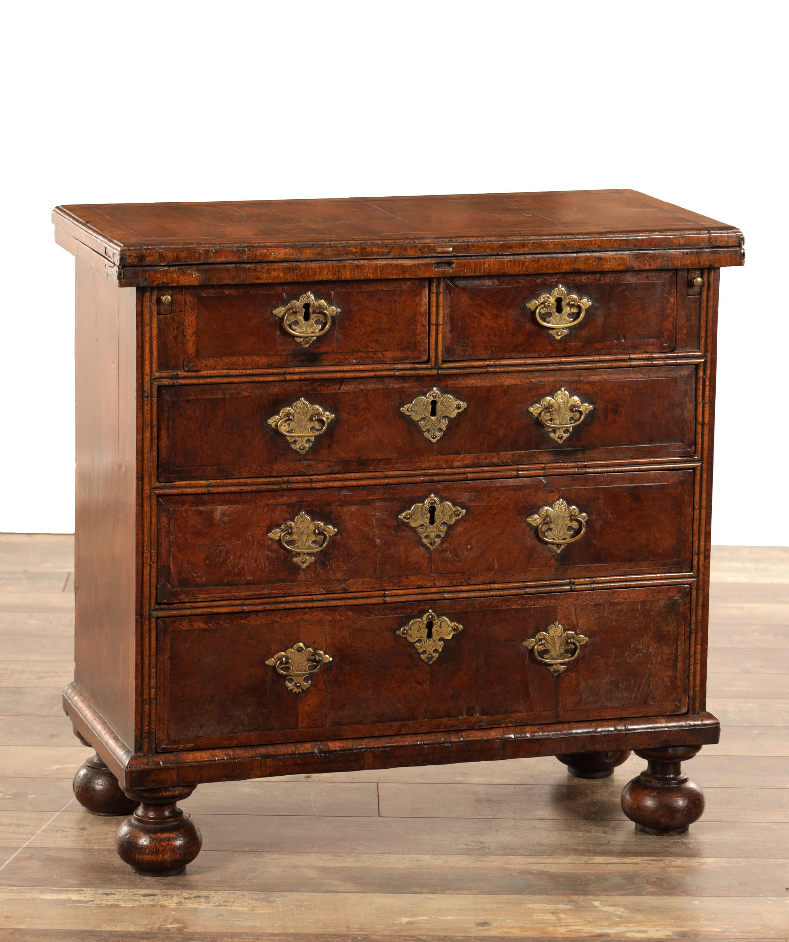A WILLIAM AND MARY HERRING-BANDED AND FIGURED WALNUT BACHELOR'S CHEST OF SMALL SIZE WITH FOLD-OVER: A WILLIAM AND MARY HERRING-BANDED AND FIGURED WALNUT BACHELOR'S CHEST OF SMALL SIZE WITH FOLD-OVER TOP above two short and three long graduated drawers with engraved brass handles and escutcheons, sup