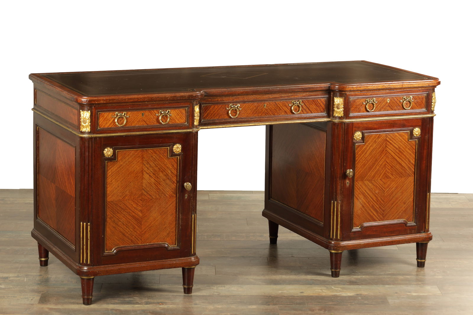A 19TH CENTURY FRENCH MAHOGANY AND SATINWOOD PEDESTAL DESK: A 19TH CENTURY FRENCH MAHOGANY AND SATINWOOD PEDESTAL DESK with an inset tooled leather top above a frieze fitted with three drawers, the twin pedestals with panelled cupboard doors, gilt bronze mount