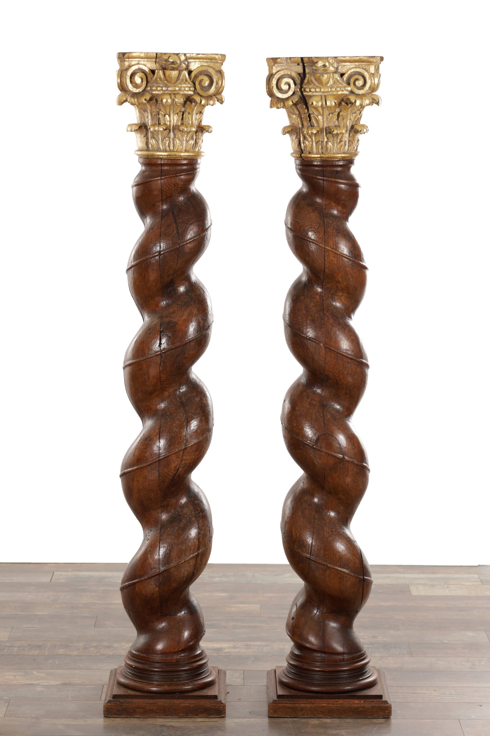 A PAIR OF EARLY 18TH CENTURY WALNUT BARLEY TWIST COLUMNS WITH GILT CORINTHIAN CAPITALS ON SQUARE: A PAIR OF EARLY 18TH CENTURY WALNUT BARLEY TWIST COLUMNS WITH GILT CORINTHIAN CAPITALS ON SQUARE PLINTH BASES the spiral-turned walnut shafts with moulded collars surmounted by gilt Corinthian capital
