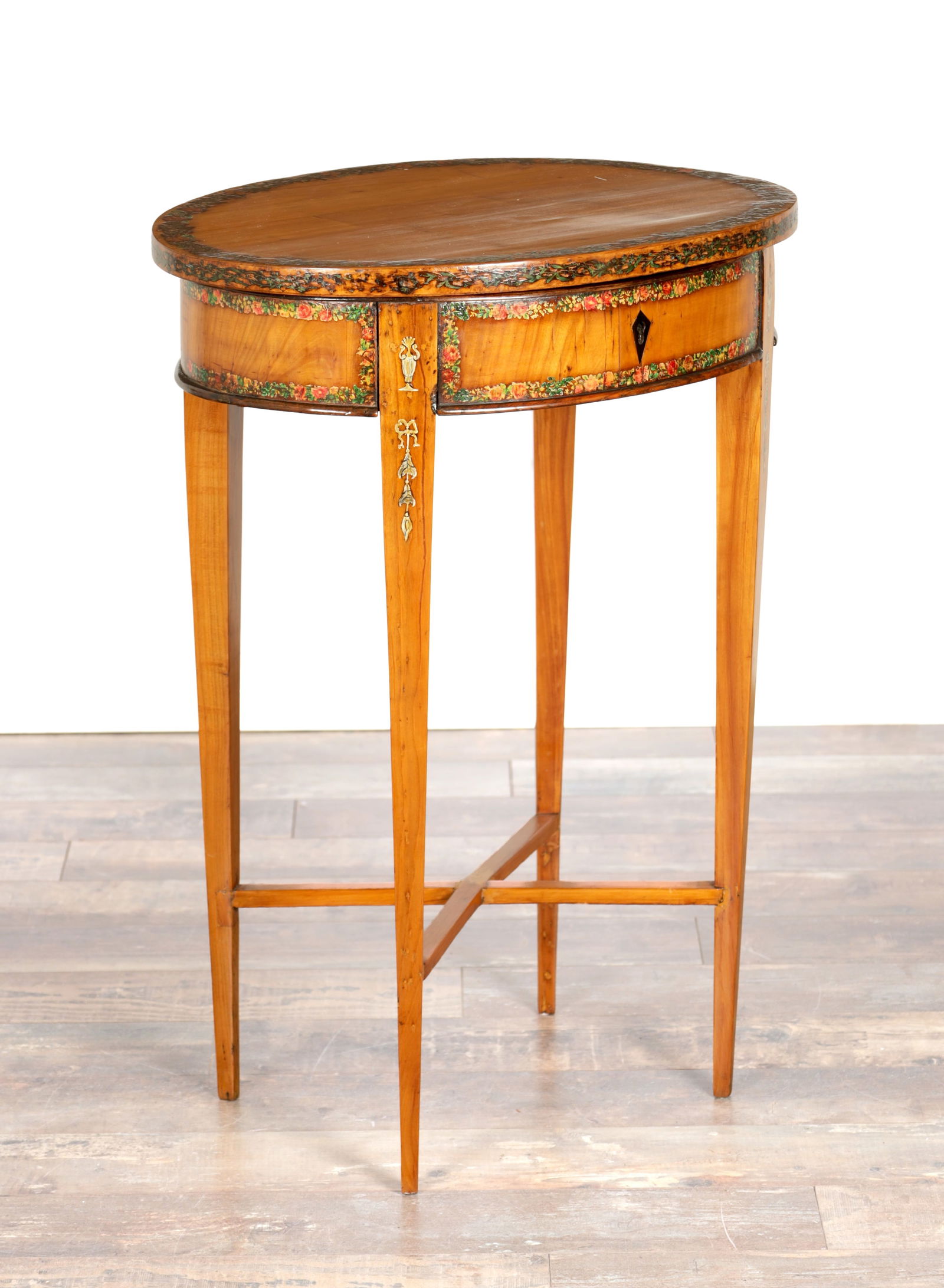 A 19TH CENTURY SHERATON STYLE PAINTED VANITY TABLE: A 19TH CENTURY SHERATON STYLE PAINTED VANITY TABLE of oval form with a hinged lid revealing a fitted interior, the frieze painted with floral garlands, raised on square tapering legs joined by an X-sh