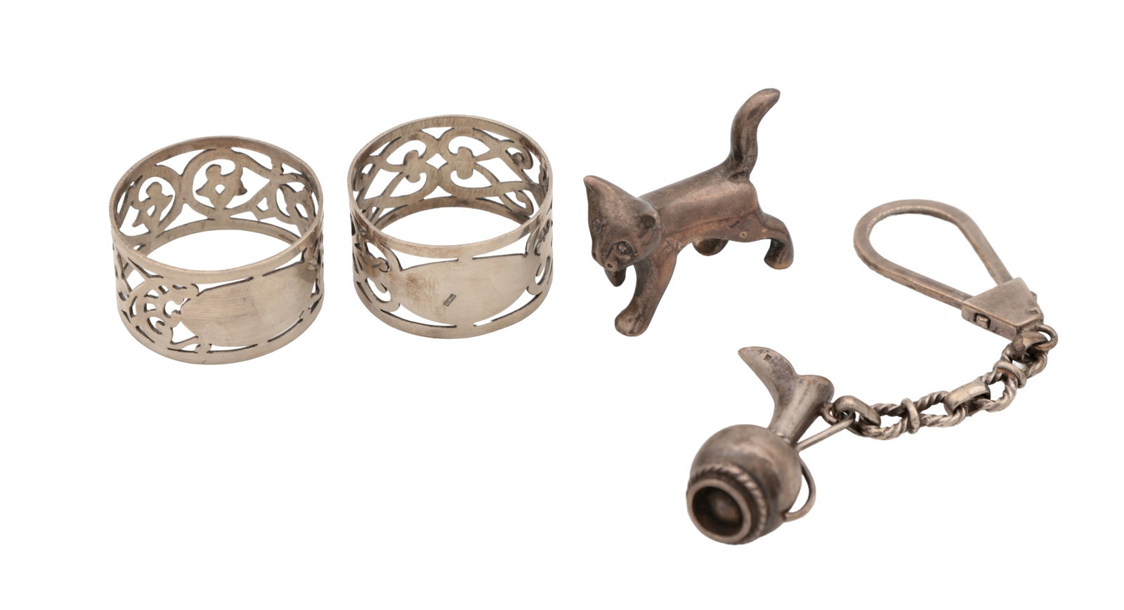 A MIXED LOT OF 20TH CENTURY EGYPTIAN SILVER: A MIXED LOT OF 20TH CENTURY EGYPTIAN SILVER comprising a small model of a cat, a keychain and a pair of pierced napkin rings with scroll ornament and vacant cartouches, all with 900 fineness marks.