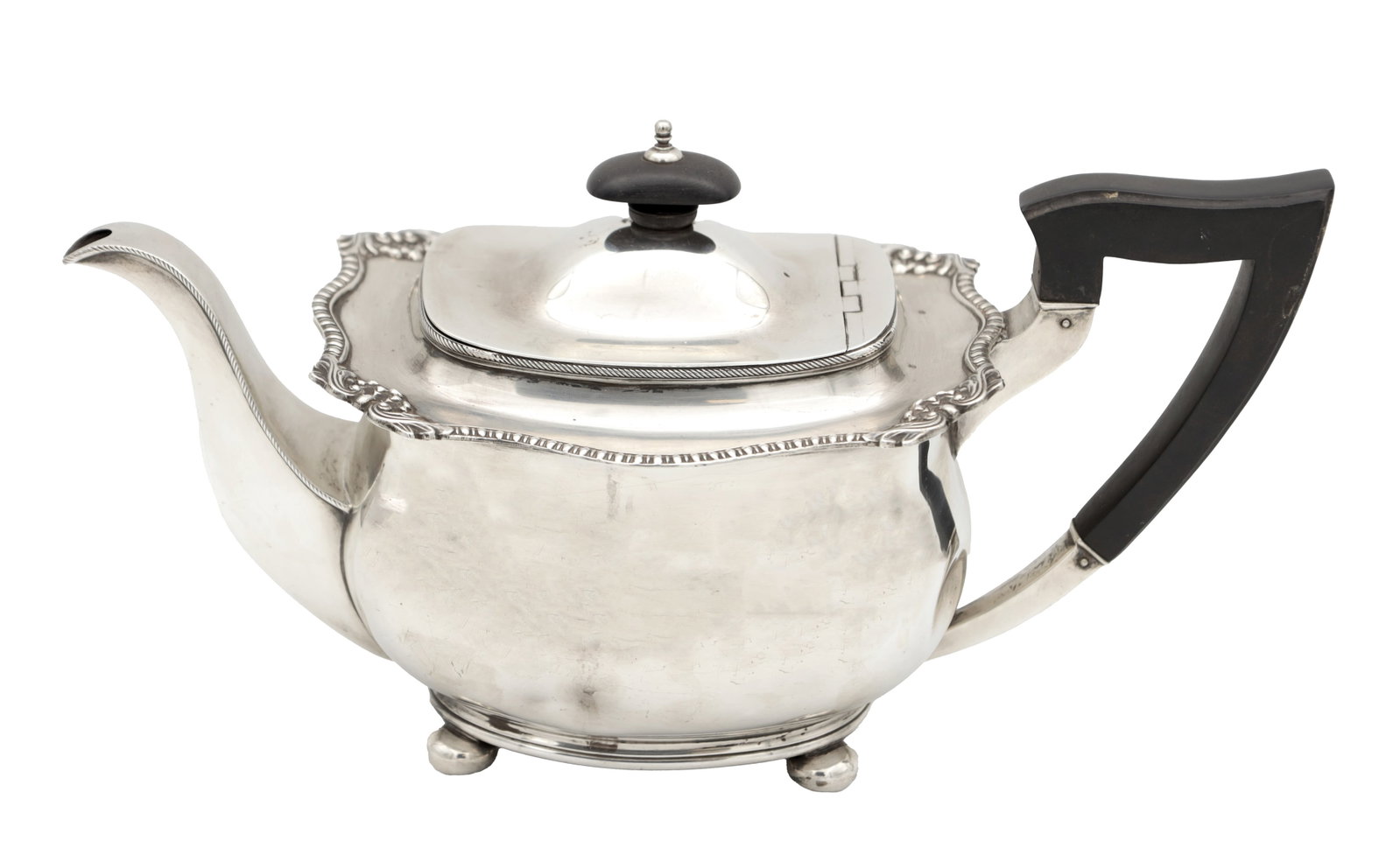 AN EARLY 20TH CENTURY ENGLISH SILVER TEAPOT WITH EBONY HANDLE AND FINIAL: AN EARLY 20TH CENTURY ENGLISH SILVER TEAPOT WITH EBONY HANDLE AND FINIAL hallmarked Sheffield 1924, of squat oval form with shaped rim and domed hinged cover, raised on four bun feet, total weight