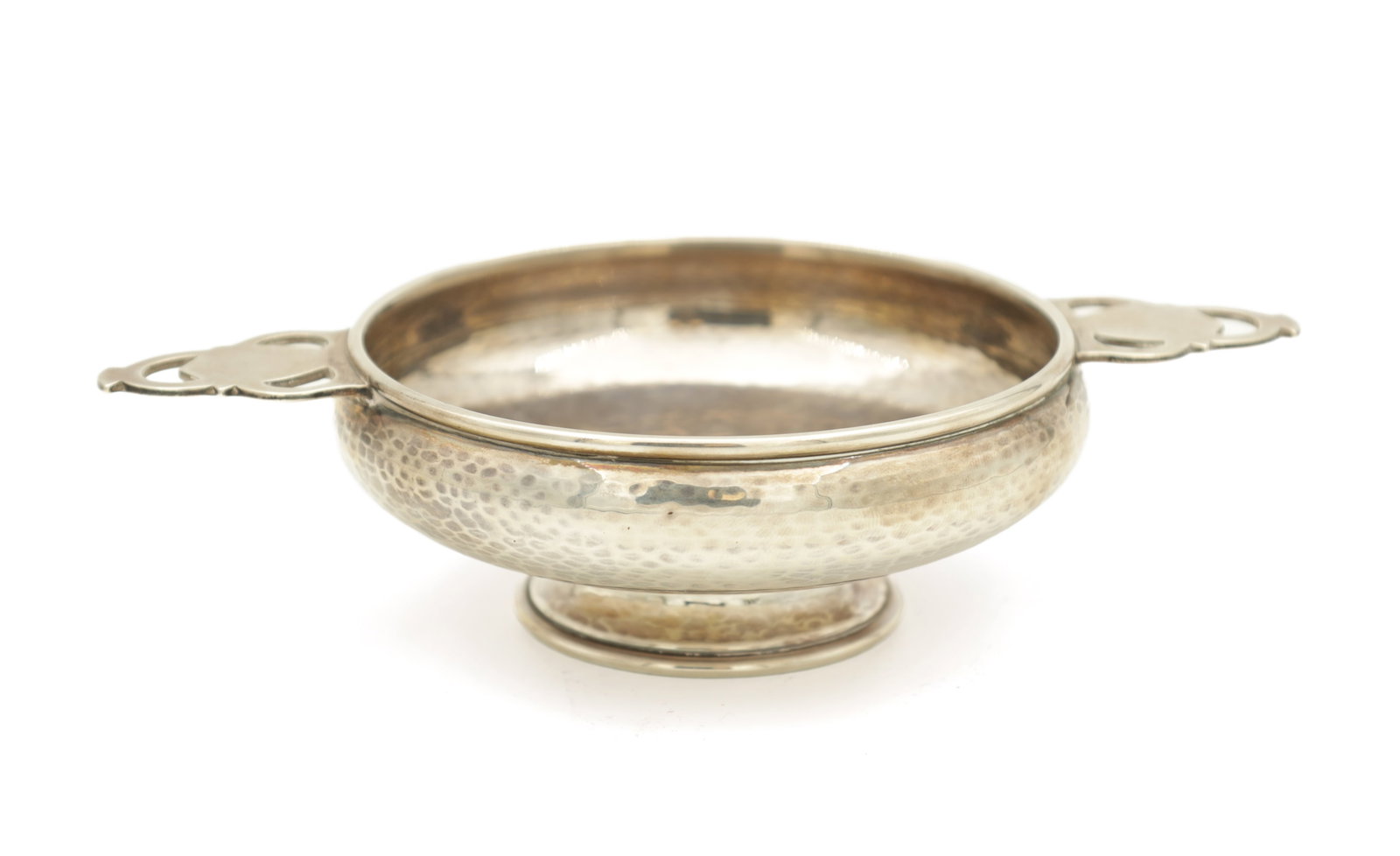 AN ARTS AND CRAFTS SILVER TWO-HANDLED BOWL: AN ARTS AND CRAFTS SILVER TWO-HANDLED BOWL of planished design with pierced handles raised on a circular foot. Total weight app. 138g. Hallmarked A.E. Jones, Birmingham. 1928. (19cm wide including