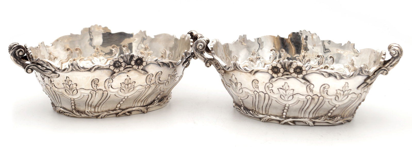 A PAIR OF EDWARDIAN ENGLISH SILVER TWO-HANDLED BASKETS: A PAIR OF EDWARDIAN ENGLISH SILVER TWO-HANDLED BASKETS hallmarked London 1906 with scalloped rims and embossed floral and scroll decoration, cast scroll handles, total weight 1100g. (24cm wide)