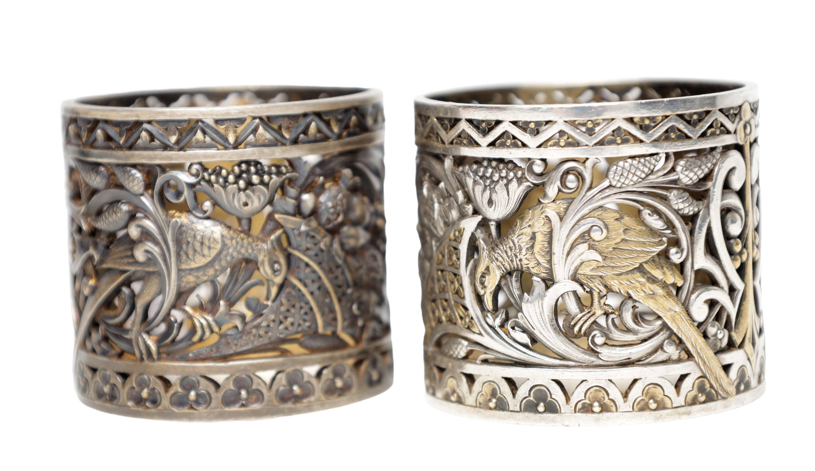 A LARGE PAIR OF PIERCED SILVER AND SILVER GILT NAPKIN RINGS: A LARGE PAIR OF PIERCED SILVER AND SILVER GILT NAPKIN RINGS with openwork decoration of pheasants amongst foliage, total app. weight 280g. (5.5cm diameter, 5cm high (each))