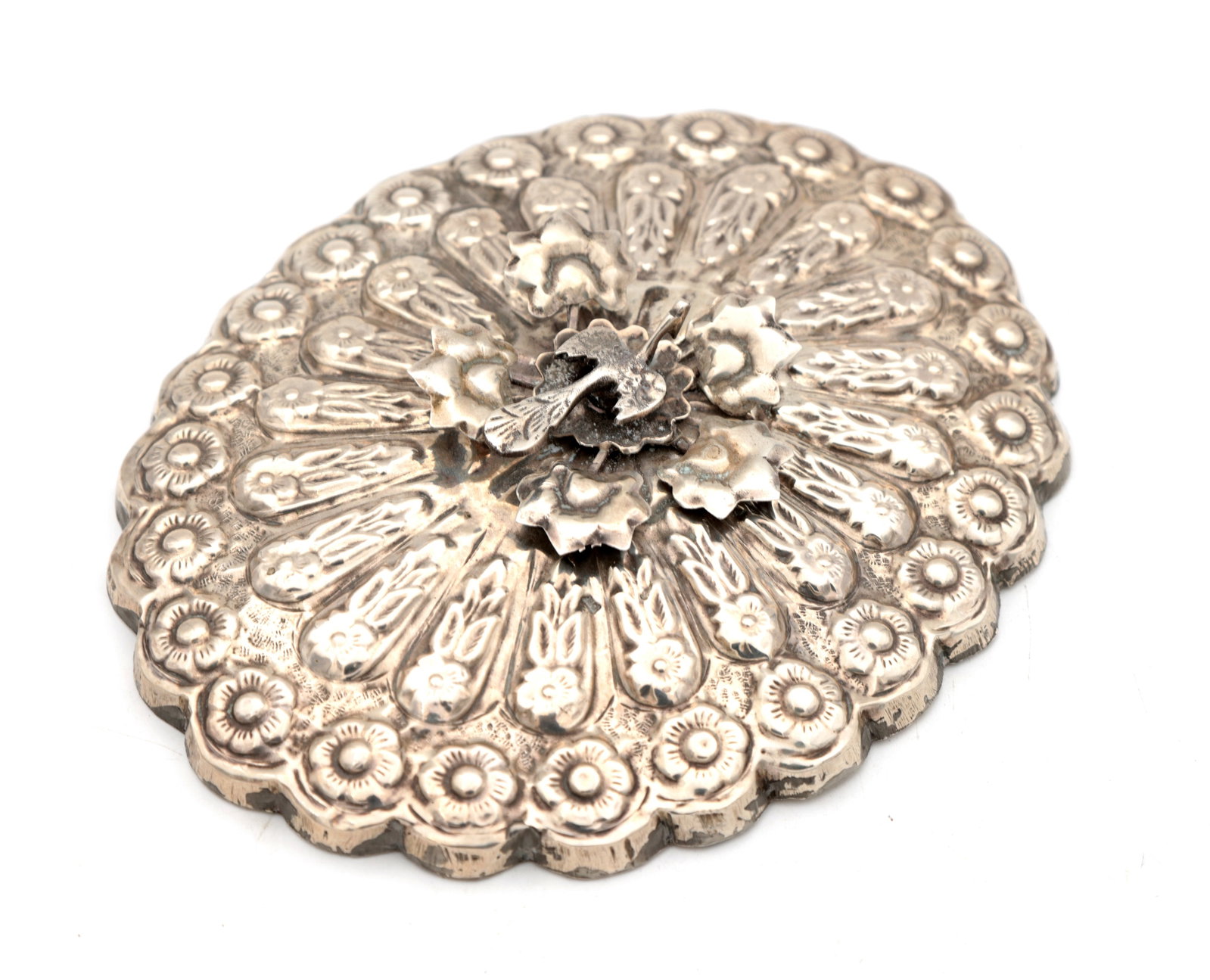 A 19TH/20TH CENTURY EASTERN SILVER MIRROR: A 19TH/20TH CENTURY EASTERN SILVER MIRROR of circular form with a scalloped rim, the back chased and repouss? with radiating petal panels and flowerhead borders centred by an applied foliate boss.
