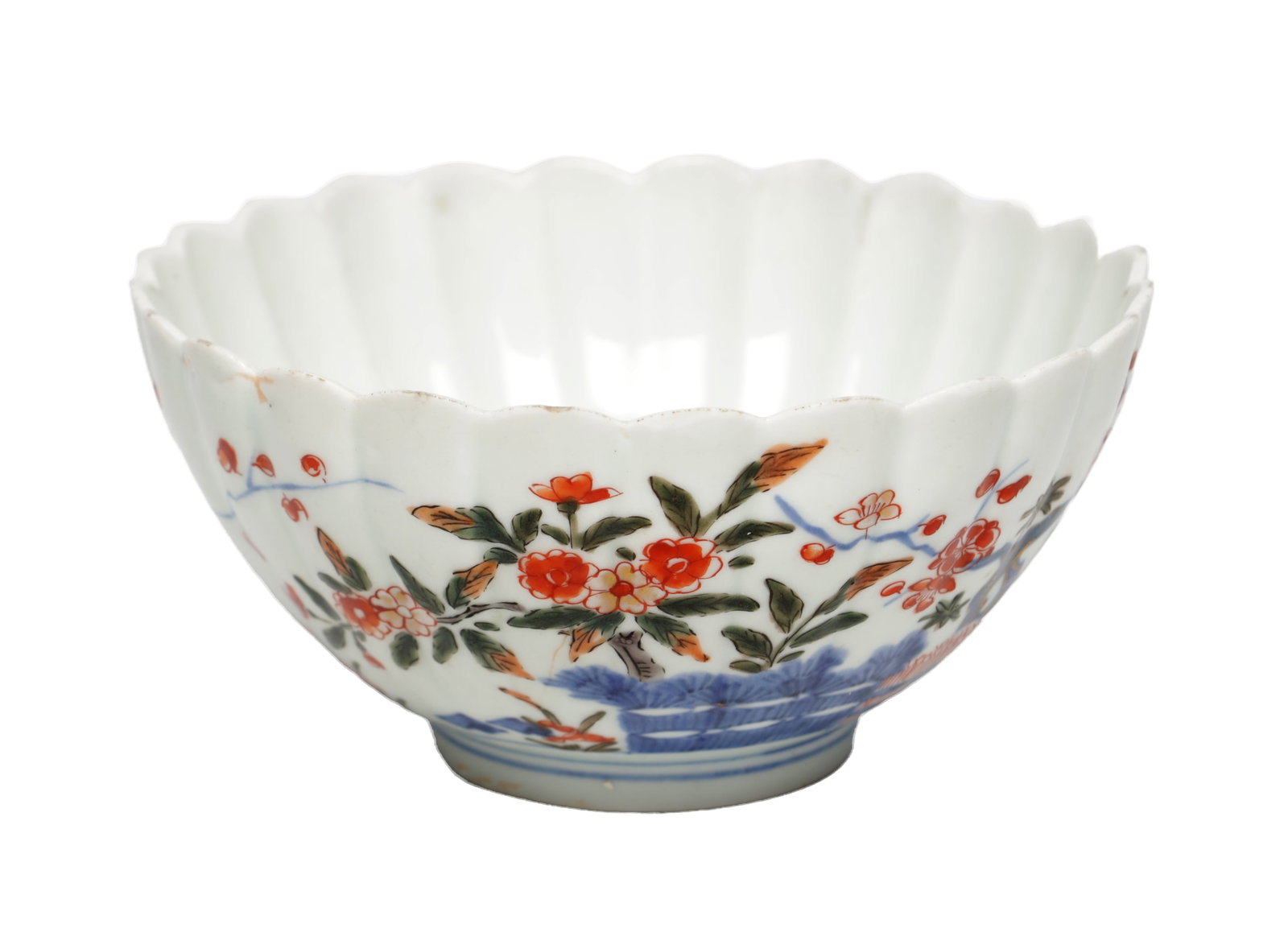 AN 18TH CENTURY JAPANESE IMARI PORCELAIN LOBED BOWL: AN 18TH CENTURY JAPANESE IMARI PORCELAIN LOBED BOWL of circular form with a scalloped rim and moulded lobed sides, enamelled in iron-red and green with flowering branches above underglaze blue rockwor
