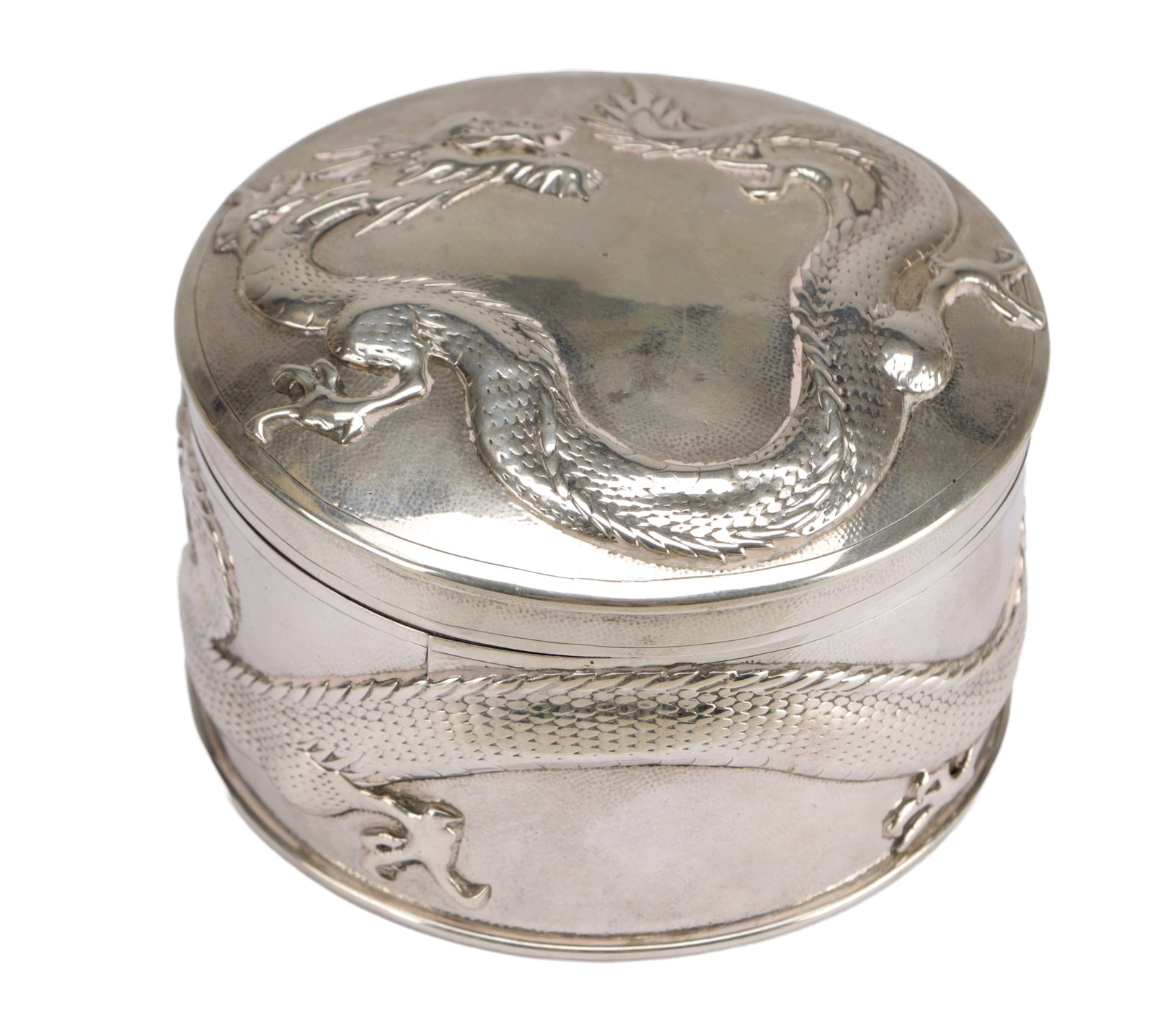 A CHINESE SILVER BOX AND COVER WITH DRAGON DECORATION: A CHINESE SILVER BOX AND COVER WITH DRAGON DECORATION of circular form, the cover and sides chased and repousse with a writhing dragon in high relief, stamped beneath Shanghai and Hungchong. (9.5cm di
