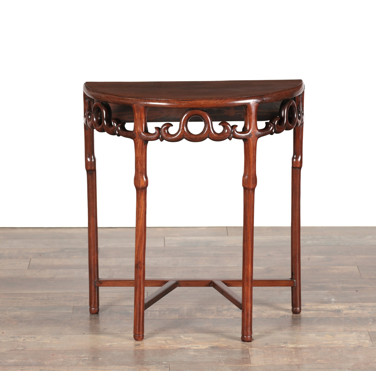 A LATE 19TH CENTURY CHINESE HARDWOOD DEMI-LUNE TABLE: A LATE 19TH CENTURY CHINESE HARDWOOD DEMI-LUNE TABLE of semi-circular form with a moulded edge and pierced ruyi scroll frieze, raised on four rounded legs united by an intersecting stretcher. (69.5cm 