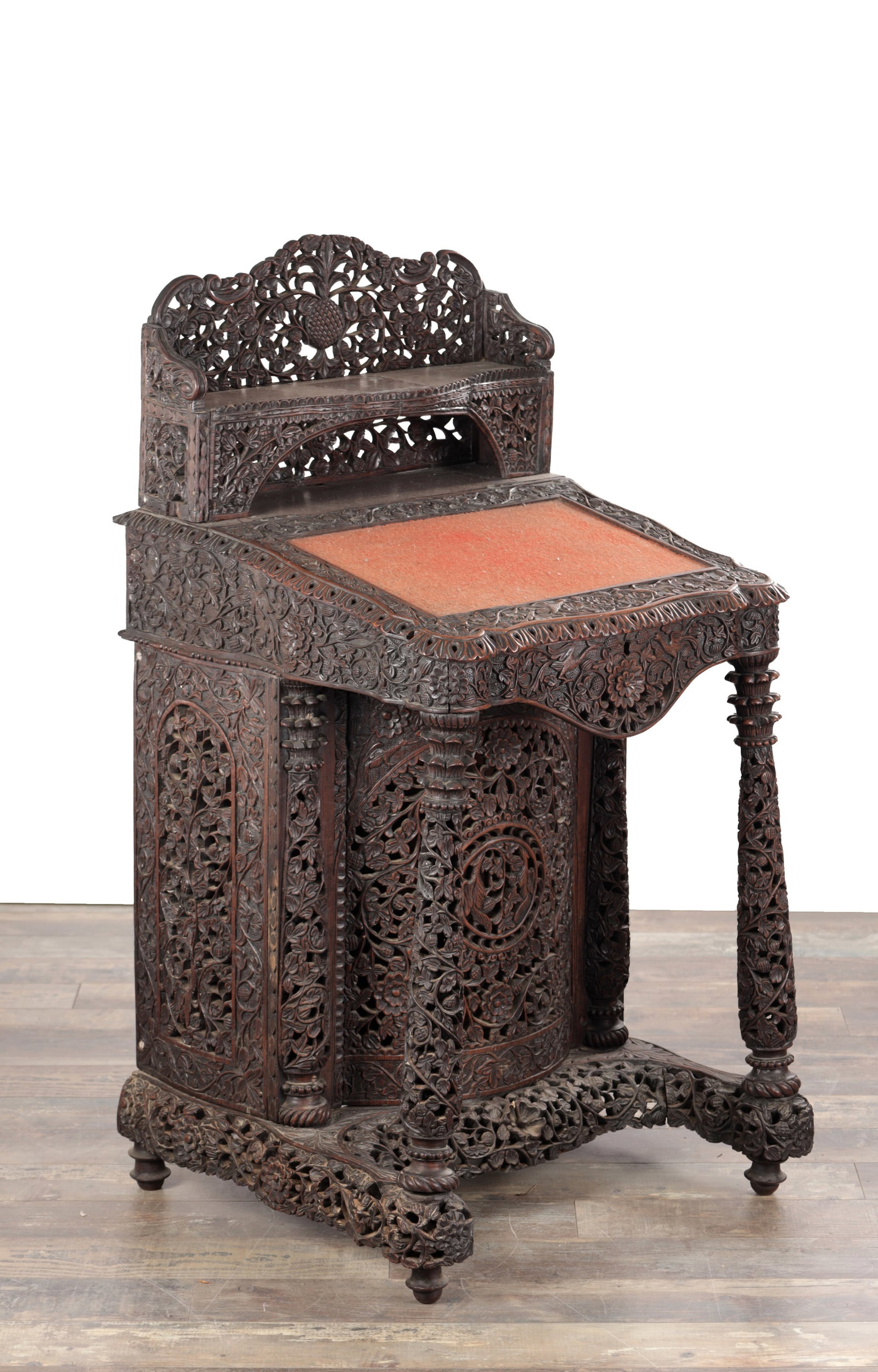 A 19TH CENTURY ANGLO INDIAN CARVED HARDWOOD DAVENPORT: A 19TH CENTURY ANGLO INDIAN CARVED HARDWOOD DAVENPORT with a pierced foliate gallery and shelf above a sloping writing surface with inset panel, the front with boldly carved spiral supports and shaped